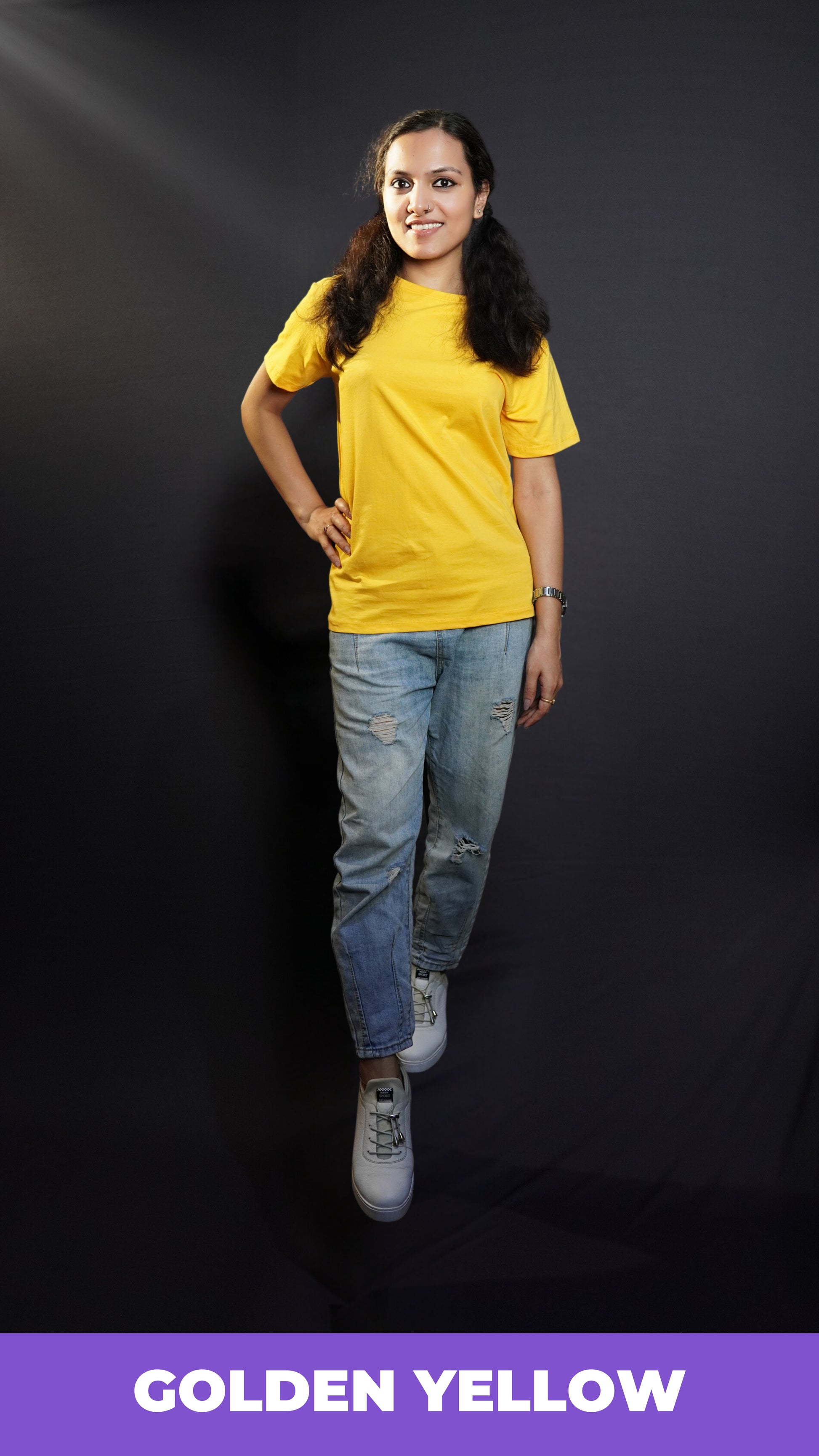 A stylish model wearing plus size stretchable golden yellow T shirt upon ripped jeans smiling brightly at the camera-Muselot