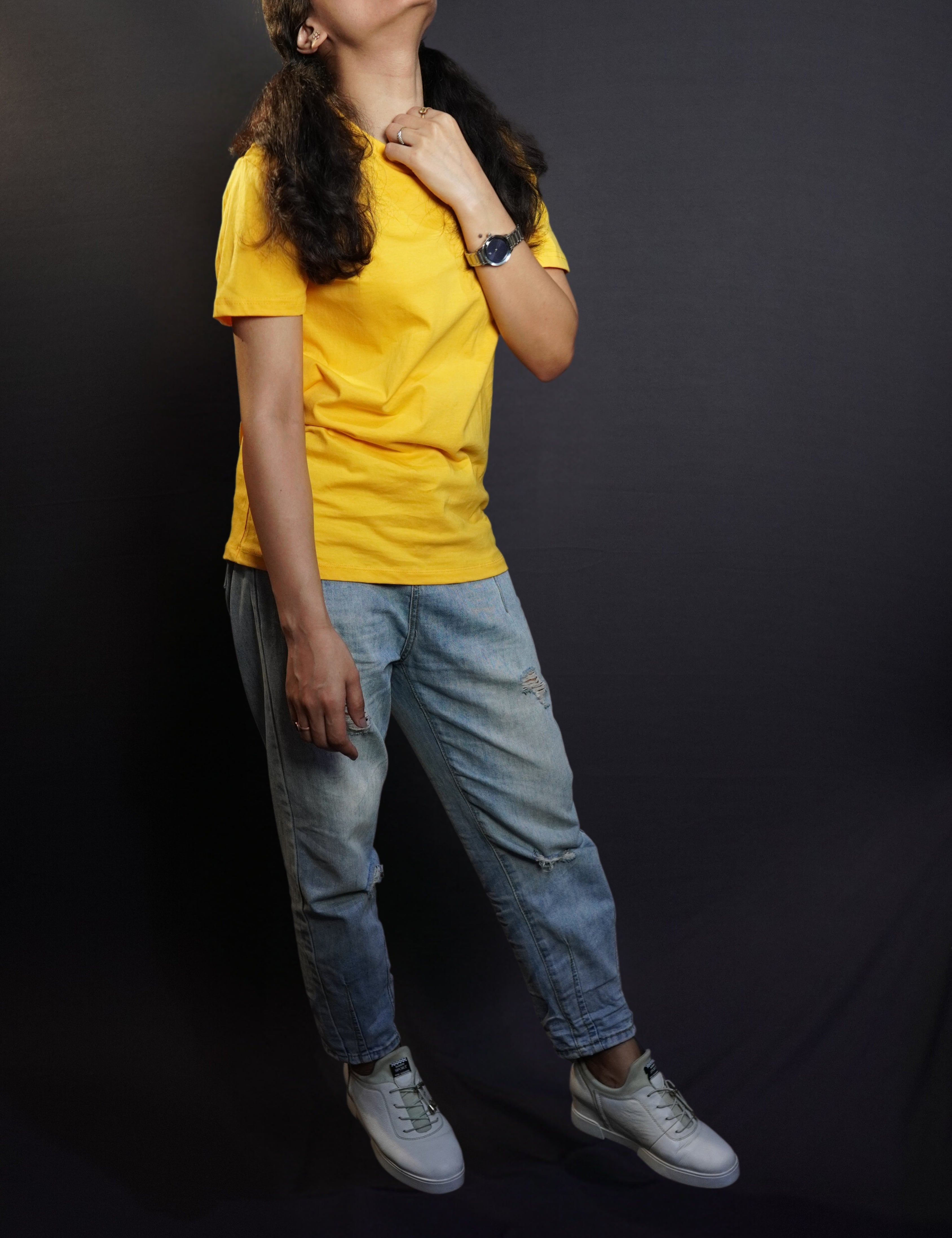 A happy woman in a casual cotton round neck short sleeved golden yellow plain T shirt paired with blue jeans and comfortable shoes-Muselot