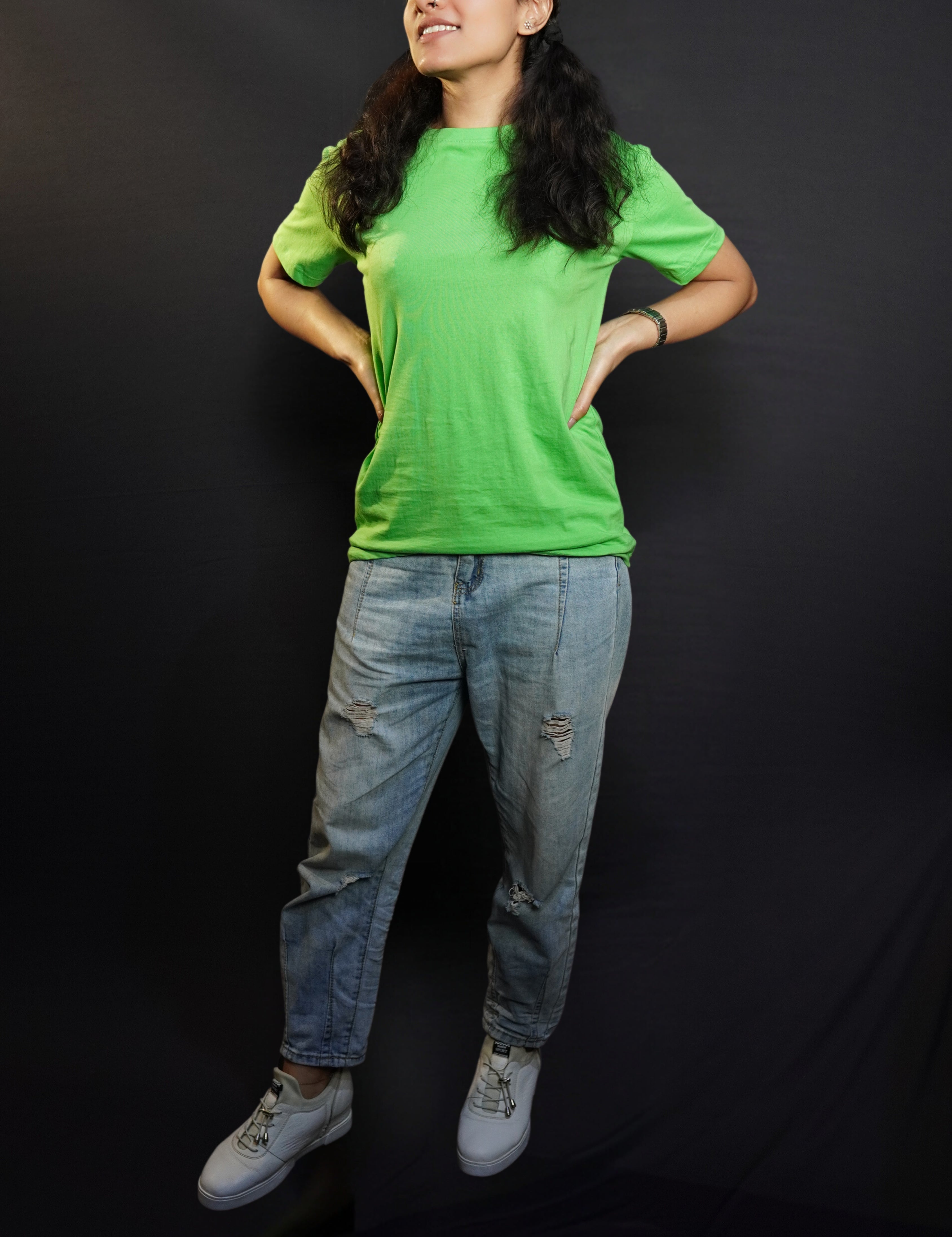 A stylish model posing with her hands on her sides looking sideways, wearing a lime green cotton long length adult's t-shirt, highlighting a trendy snug fit-Muselot