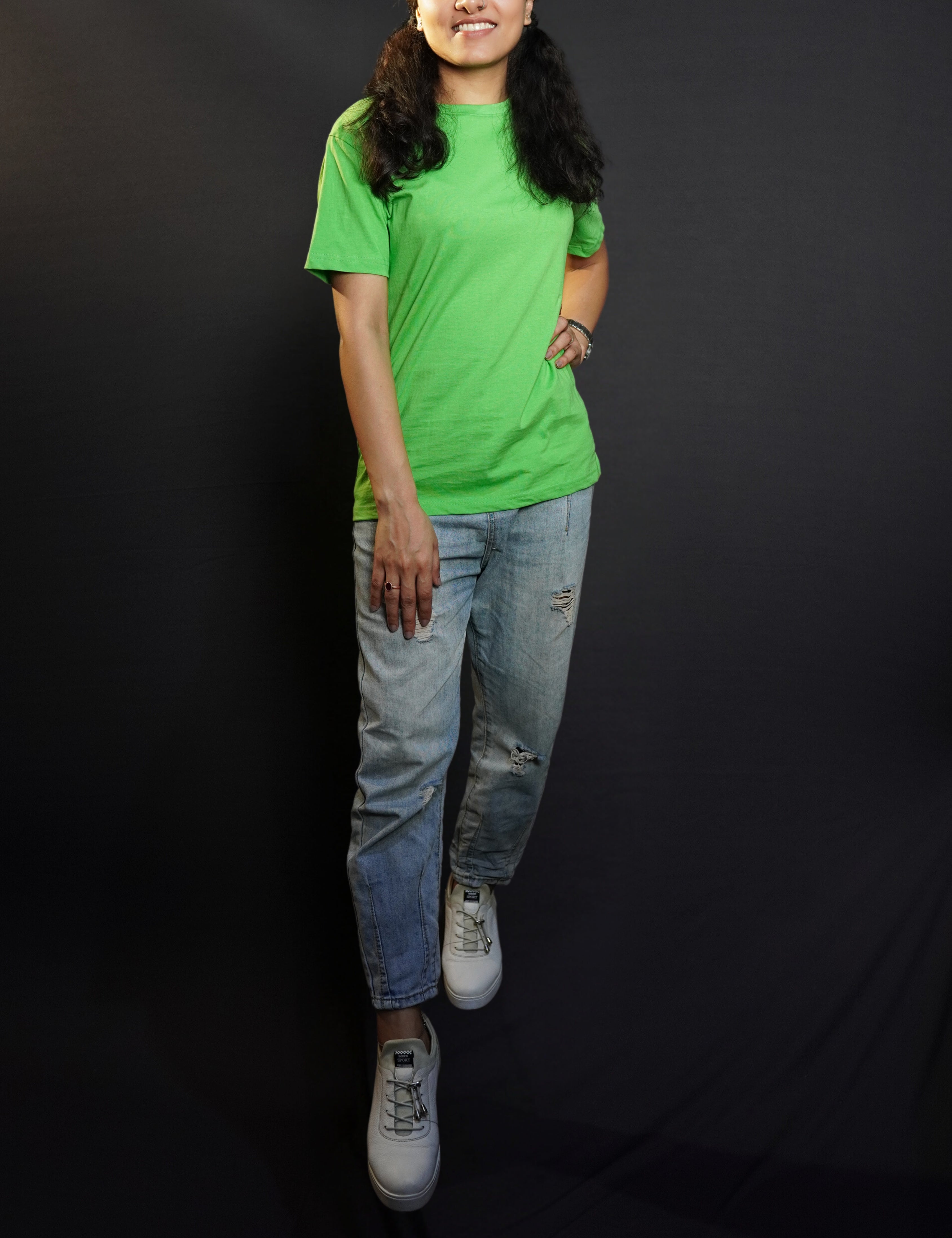 An elegant model wearing a liril green quick drying plain long length t-shirt, posing confidently with her hand on her waist and another on her thigh, smiling brightly, showcasing a modern informal look-Muselot