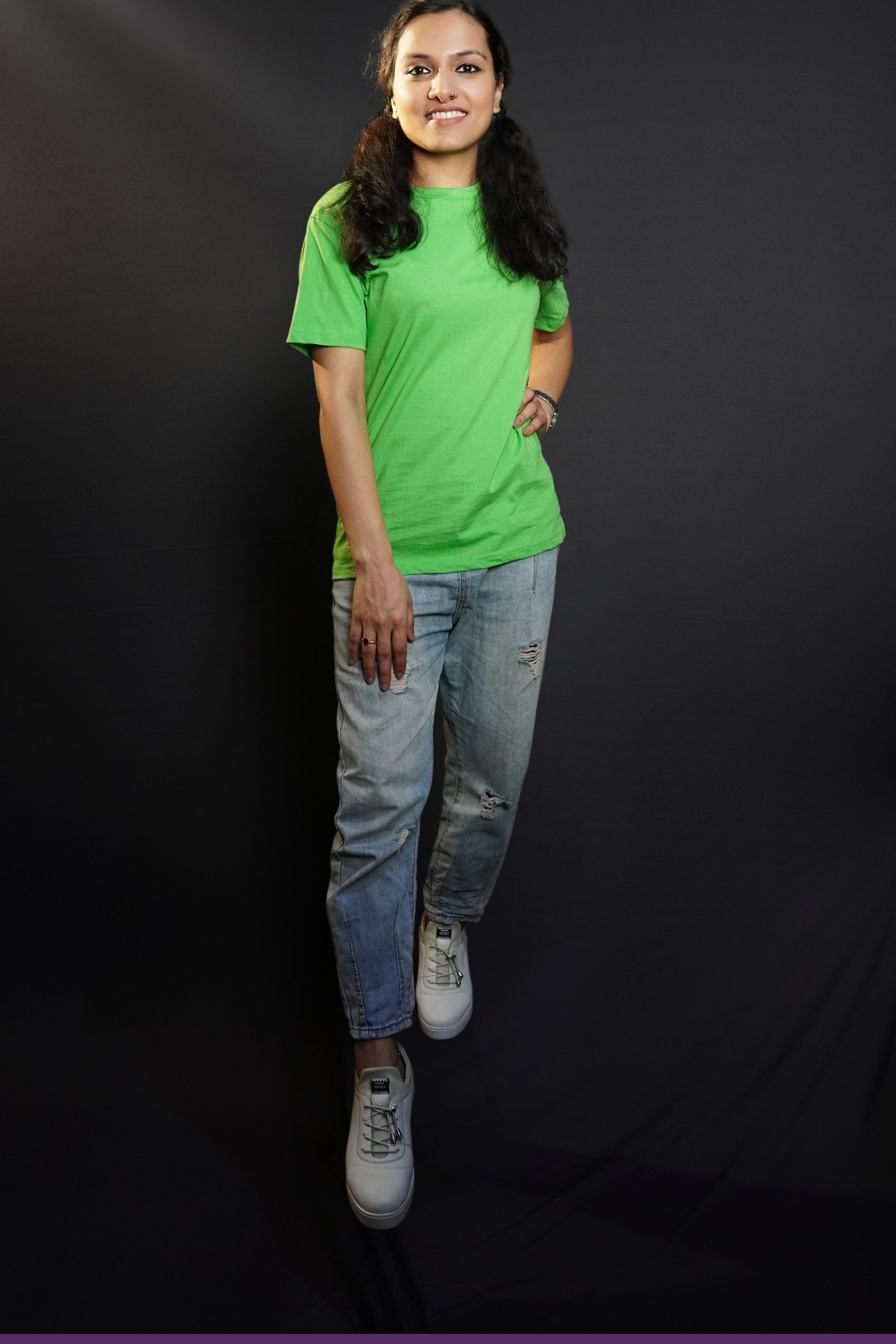 An elegant model wearing a liril green quick drying plain long length t-shirt, posing confidently with her hand on her waist and another on her thigh, smiling brightly, showcasing a modern informal look-Muselot