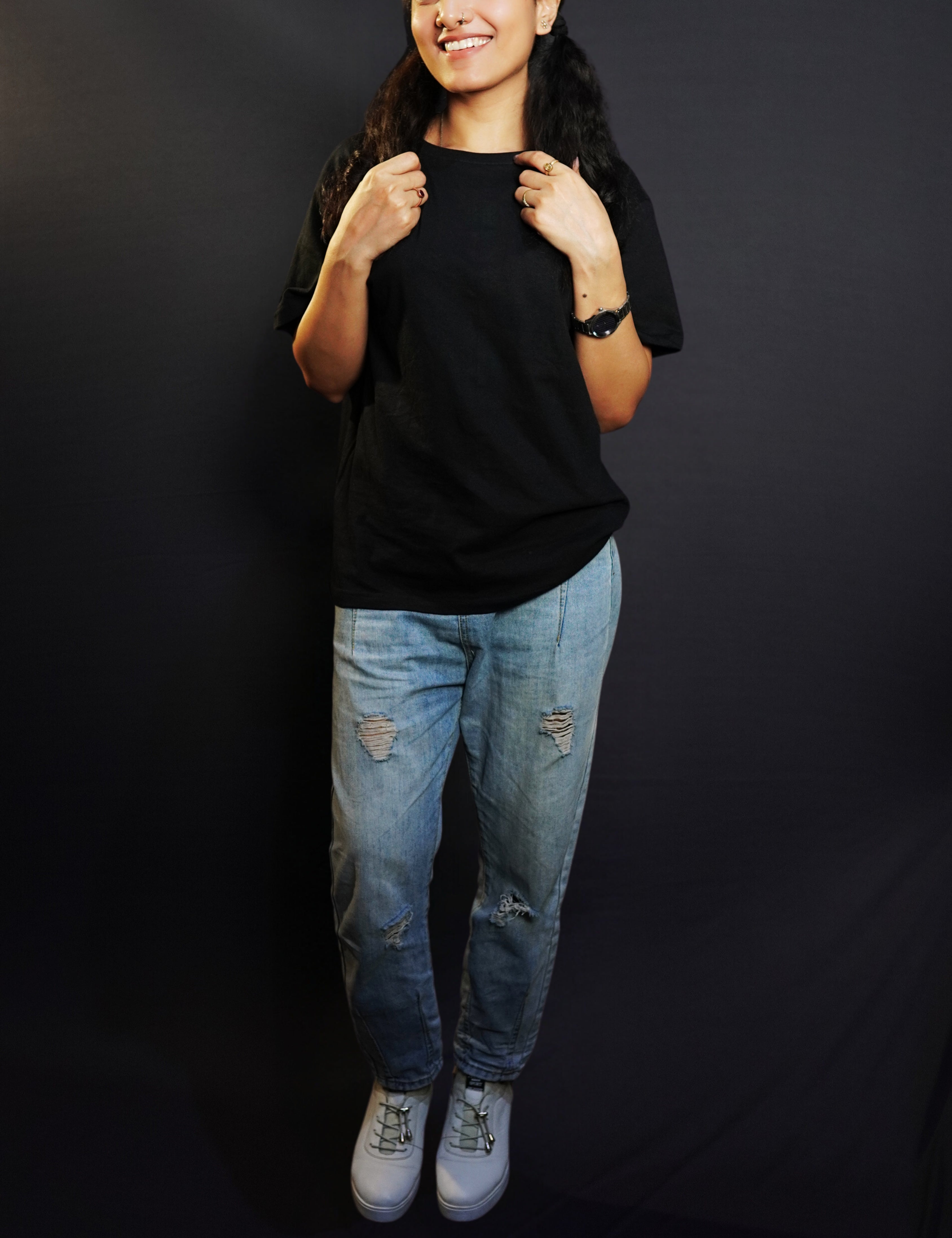 A happy woman wearing a plain round neck long length quick drying midnight black t-shirt, posing with her hands grabbing the last sections of her hair parted in two, showcasing a stylish perfect fit-Muselot