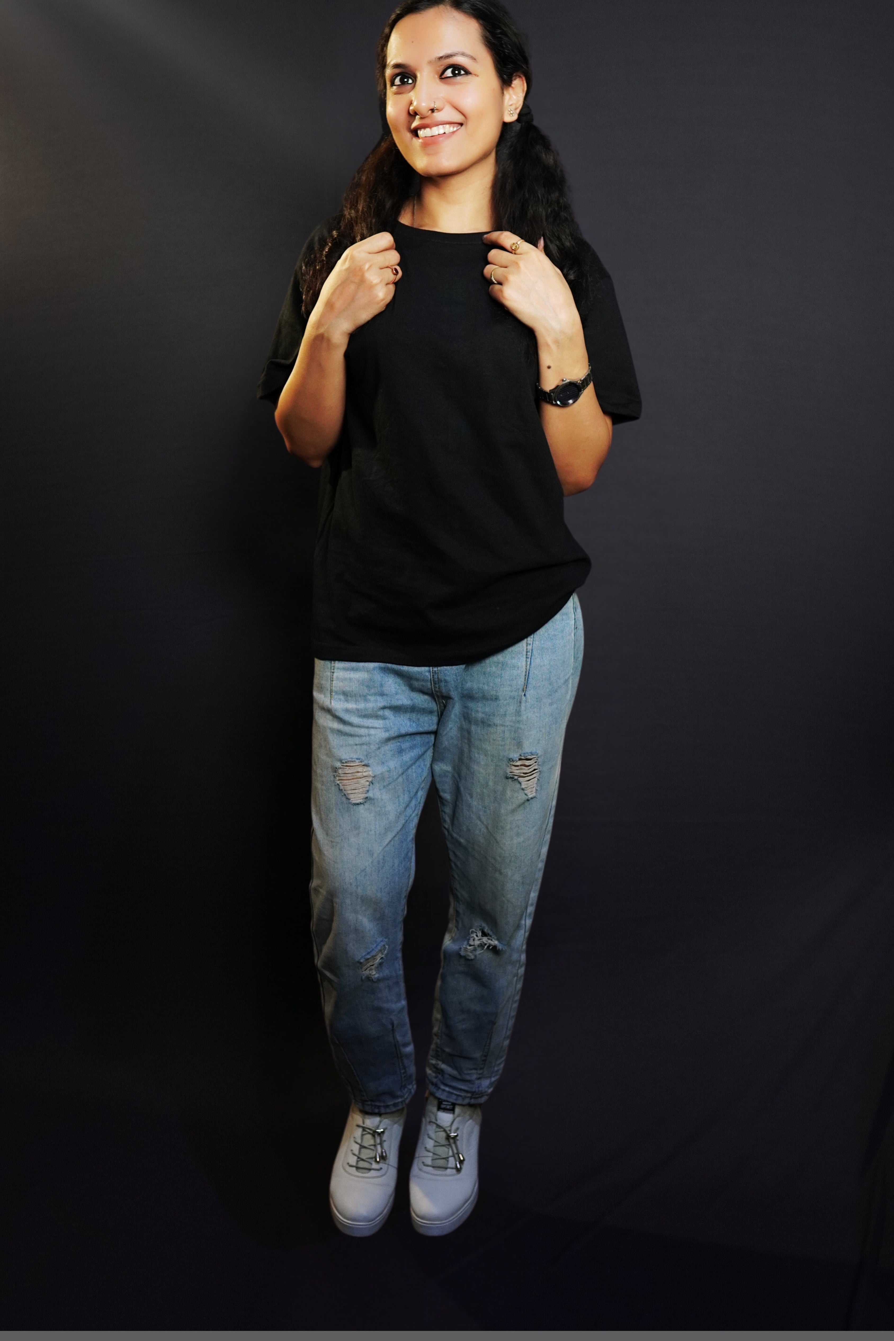 A happy woman wearing a plain round neck long length quick drying midnight black t-shirt, posing with her hands grabbing the last sections of her hair parted in two, showcasing a stylish perfect fit-Muselot