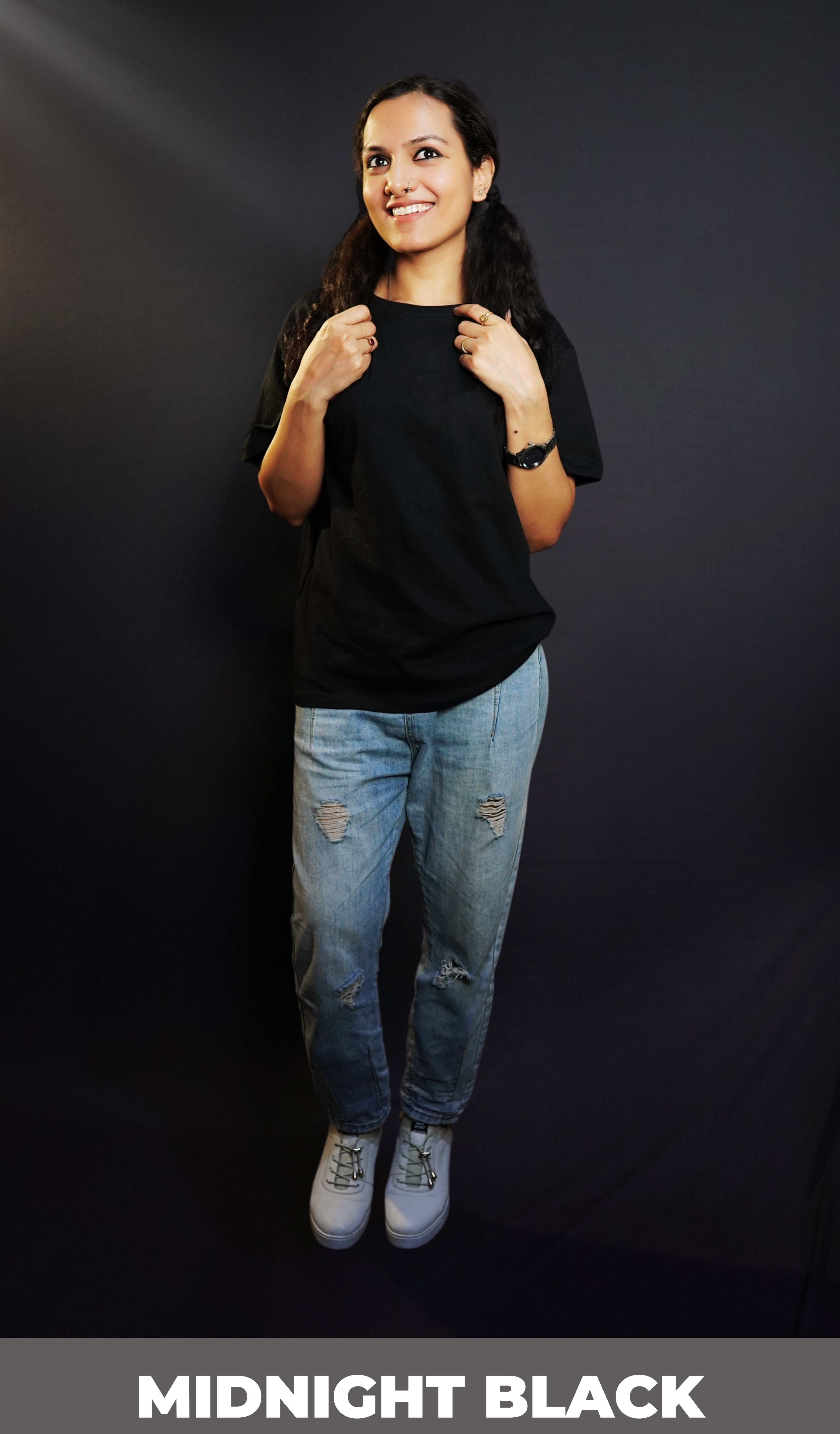 A happy woman wearing a plain round neck long length quick drying midnight black t-shirt, posing with her hands grabbing the last sections of her hair parted in two, showcasing a stylish perfect fit-Muselot