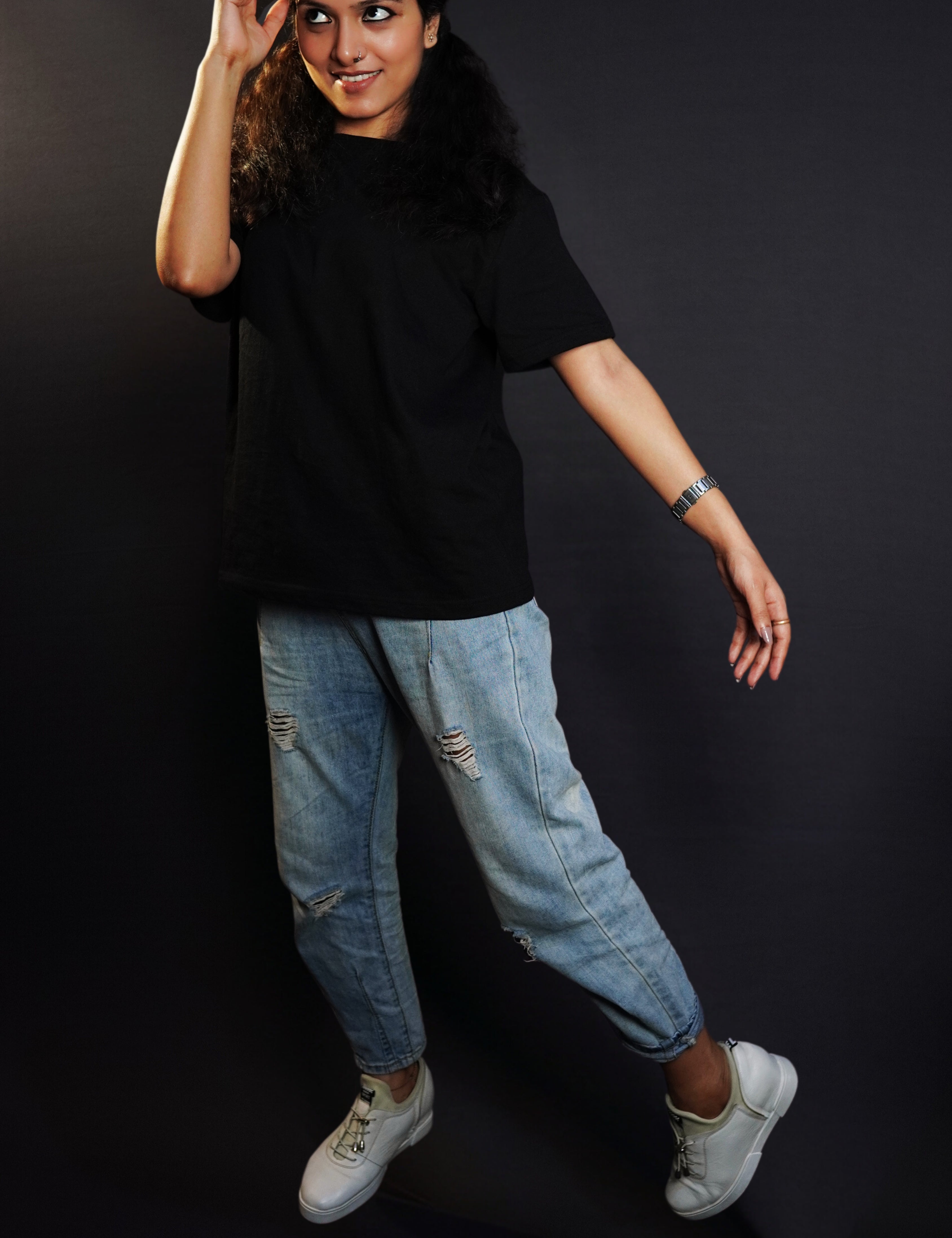 A woman posing with her hand barely touching her forehead as she sways at her side, wearing a round neck short sleeved stretchable moisture wicking midnight black t-shirt, highlighting a modern easygoing fit-Muselot