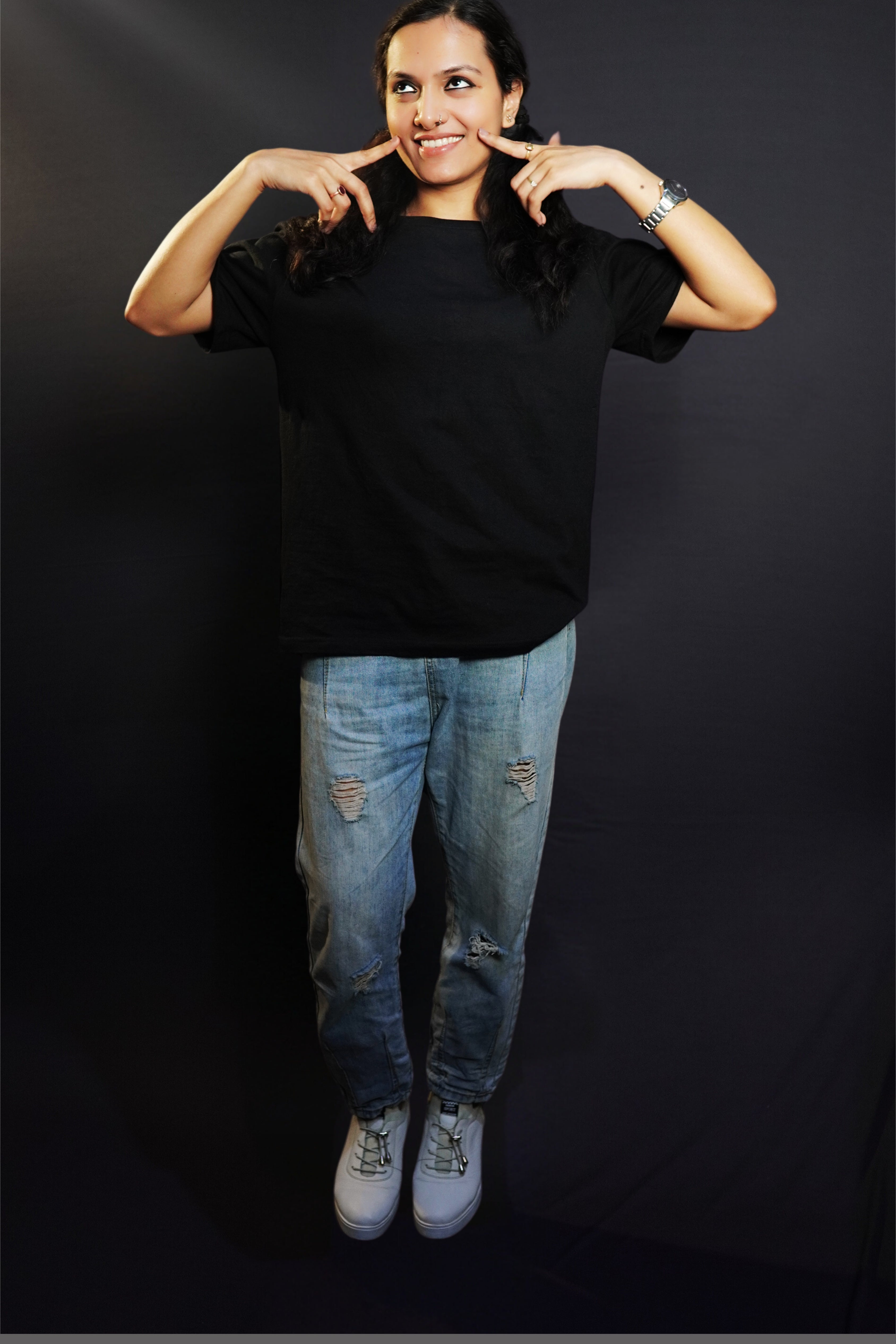 A happy woman posing with her fingers on her cheeks smiling brightly, wearing a unisex plain midnight black round neck t-shirt, showcasing a cute casual fit-Muselot