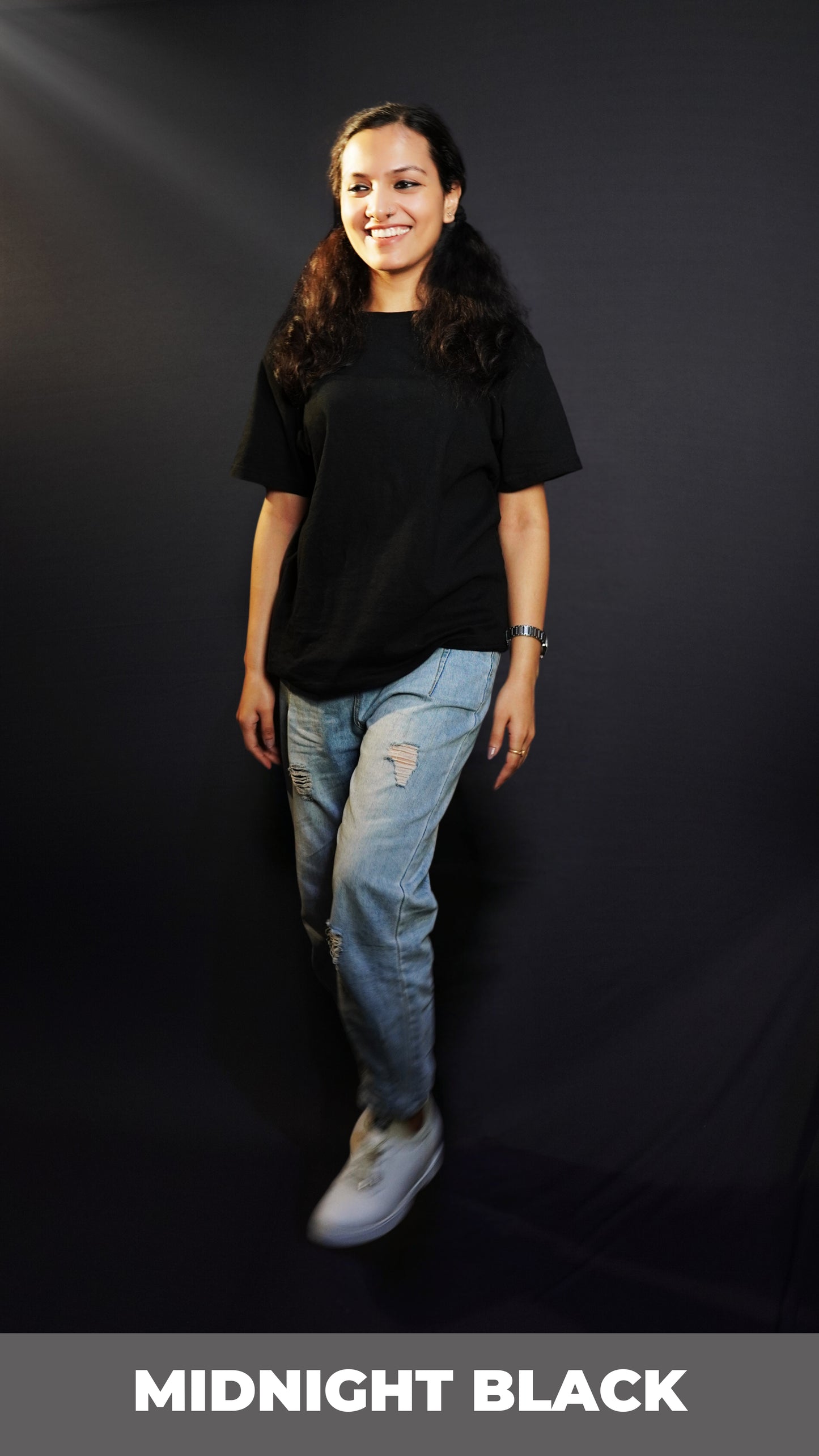 A woman walking casually against a dark background, wearing a men's round neck stretchable plain midnight black cotton t-shirt, showcasing a everyday cozy fit-Muselot