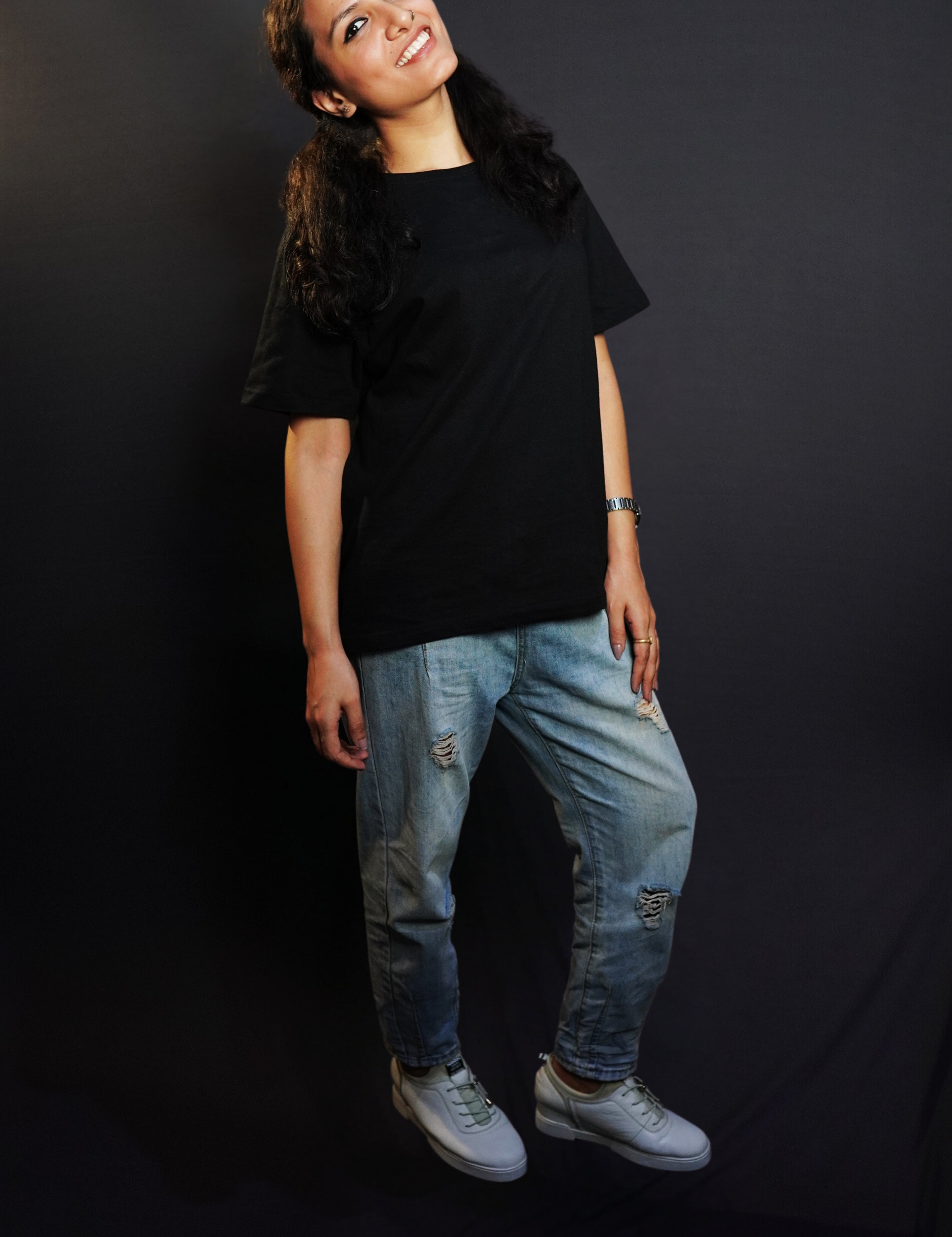 A woman posing happily with her slightly backwards and her gently resting on her thigh, wearing a plain short sleeved long length cotton midnight black t-shirt, showcasing an informal relaxed look-Muselot