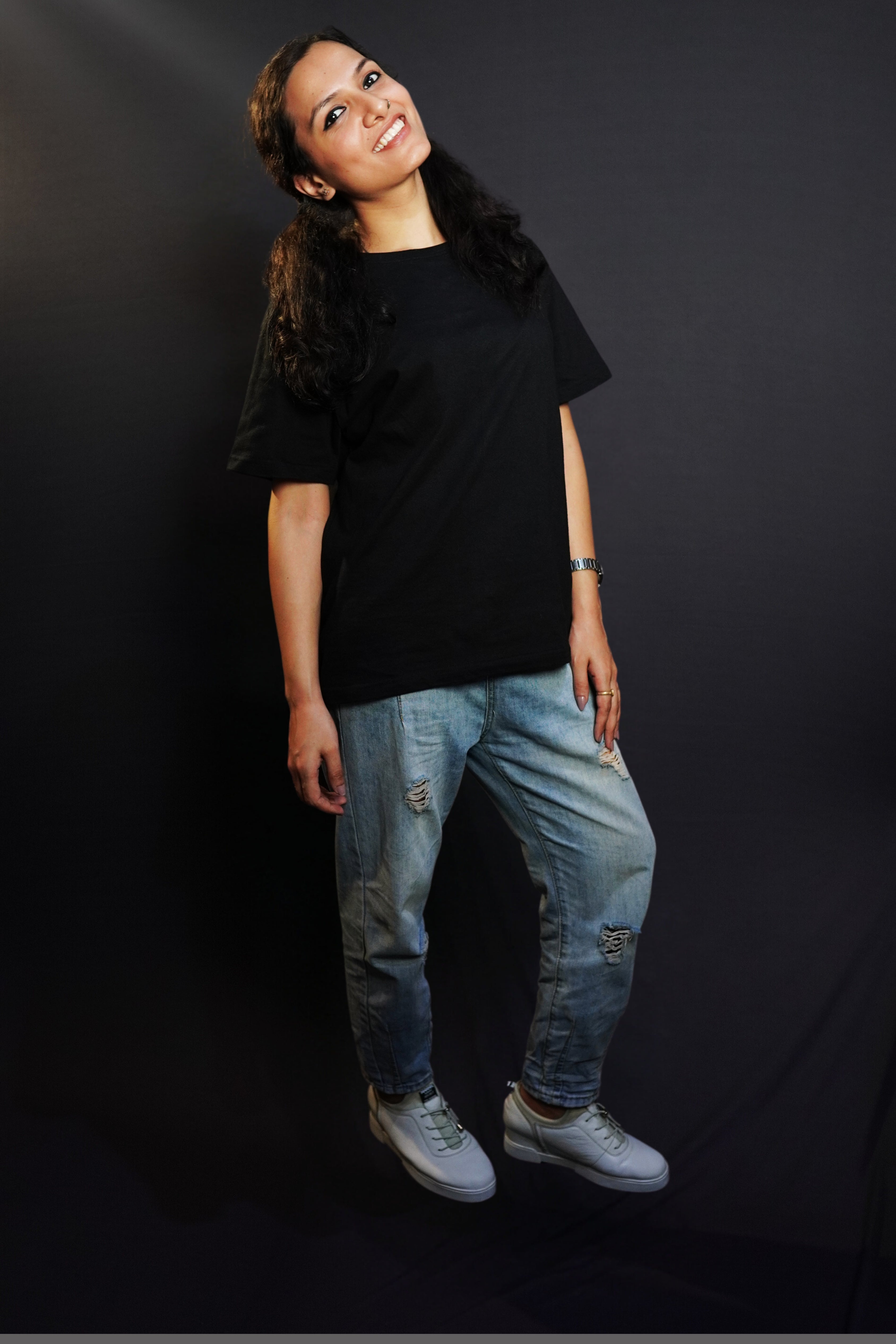 A woman posing happily with her slightly backwards and her gently resting on her thigh, wearing a plain short sleeved long length cotton midnight black t-shirt, showcasing an informal relaxed look-Muselot