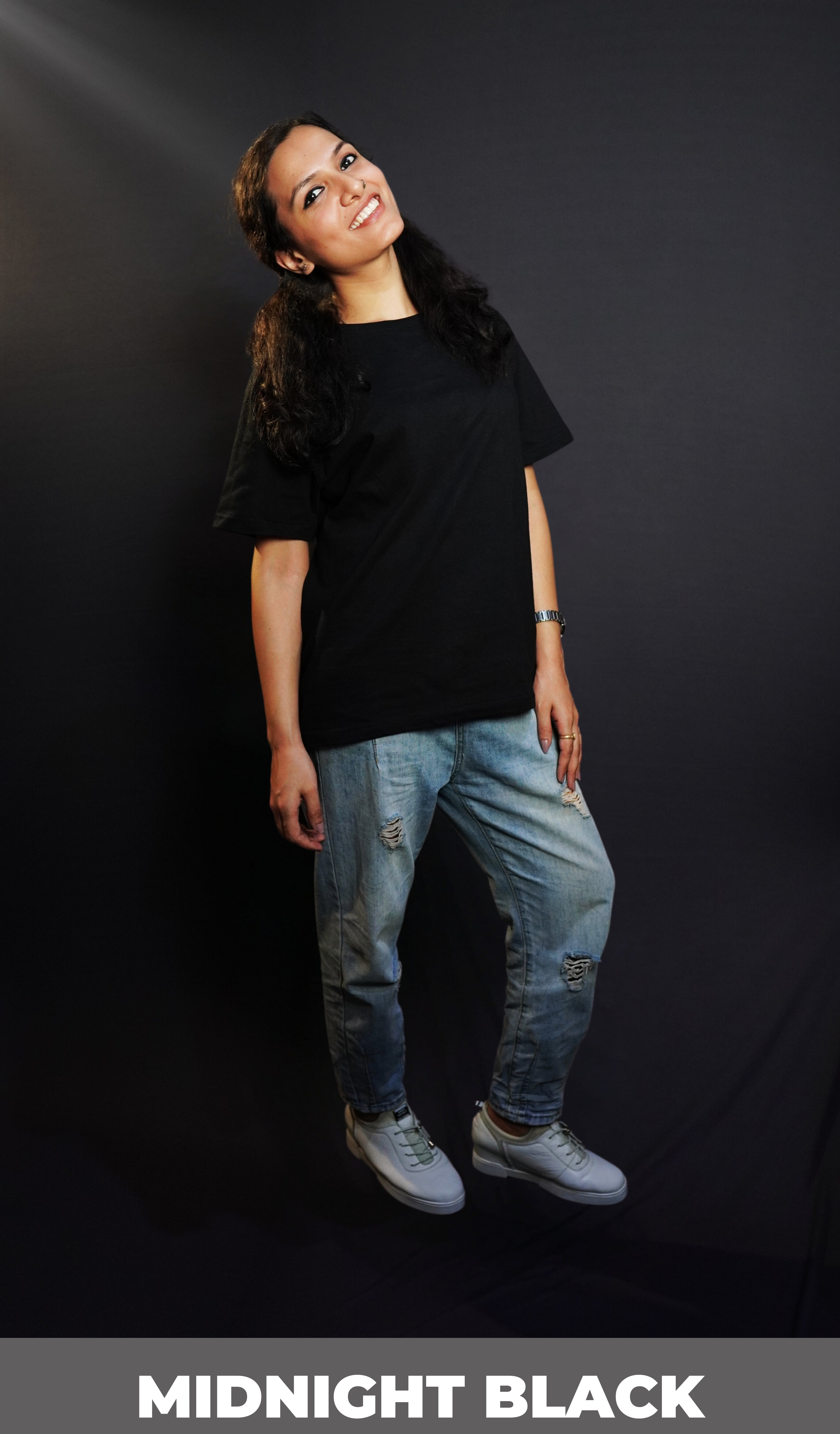 A woman posing happily with her slightly backwards and her gently resting on her thigh, wearing a plain short sleeved long length cotton midnight black t-shirt, showcasing an informal relaxed look-Muselot