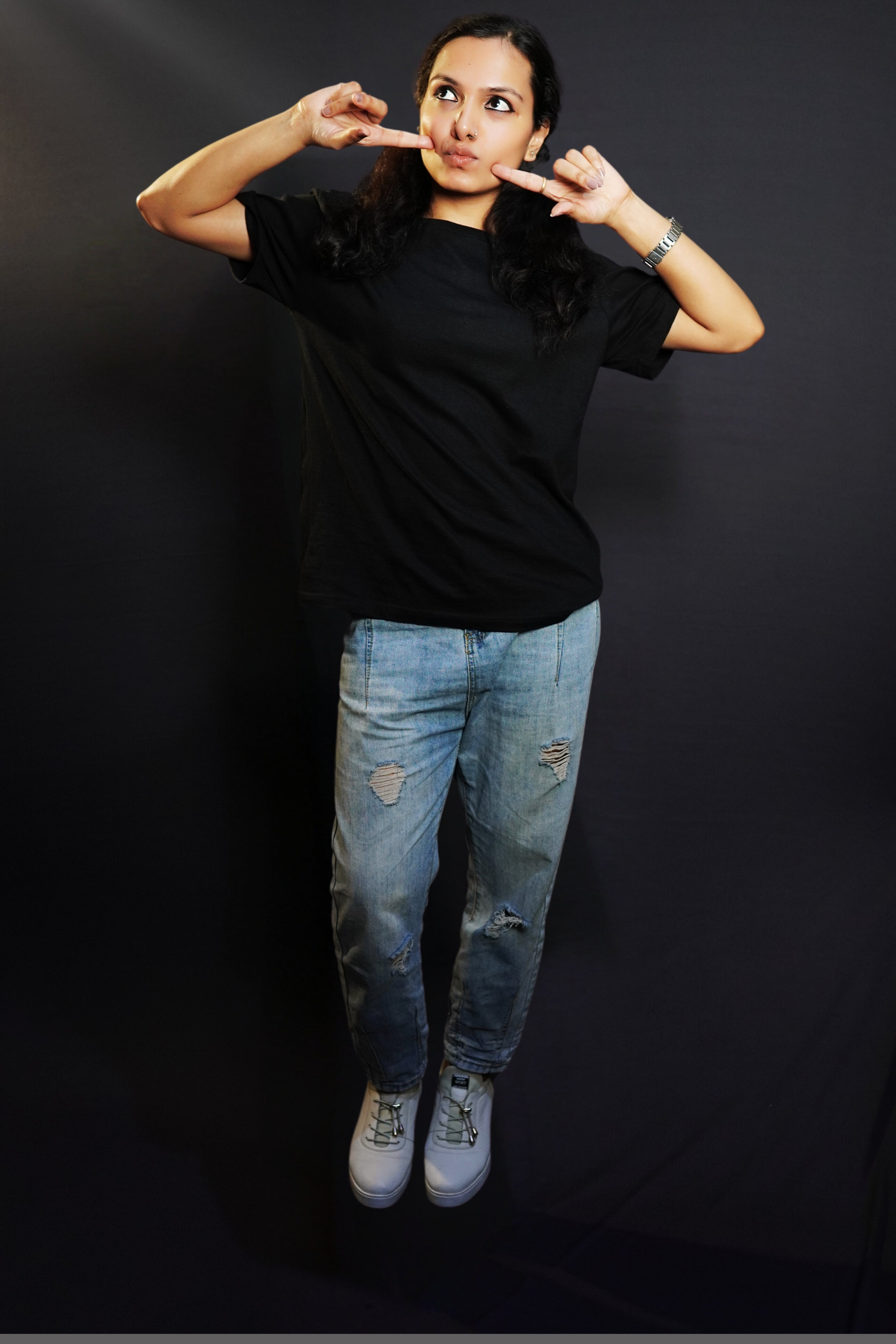 A woman in a plain adult's midnight black t-shirt with round neck, short sleeves and long length, posing with her fingers poking her cheeks, pouting a little, highlighting a cute informal look-Muselot