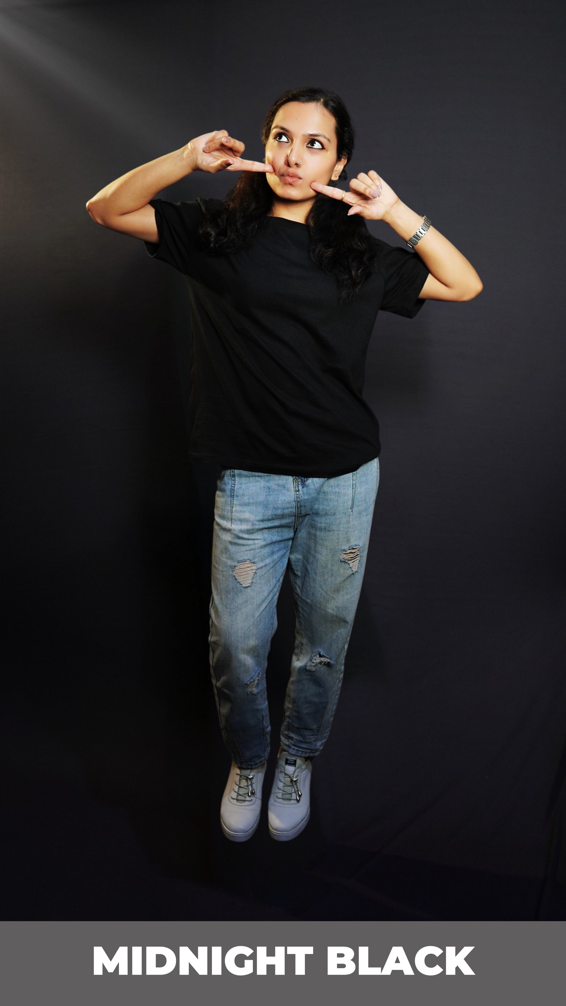 A woman in a plain adult's midnight black t-shirt with round neck, short sleeves and long length, posing with her fingers poking her cheeks, pouting a little, highlighting a cute informal look-Muselot