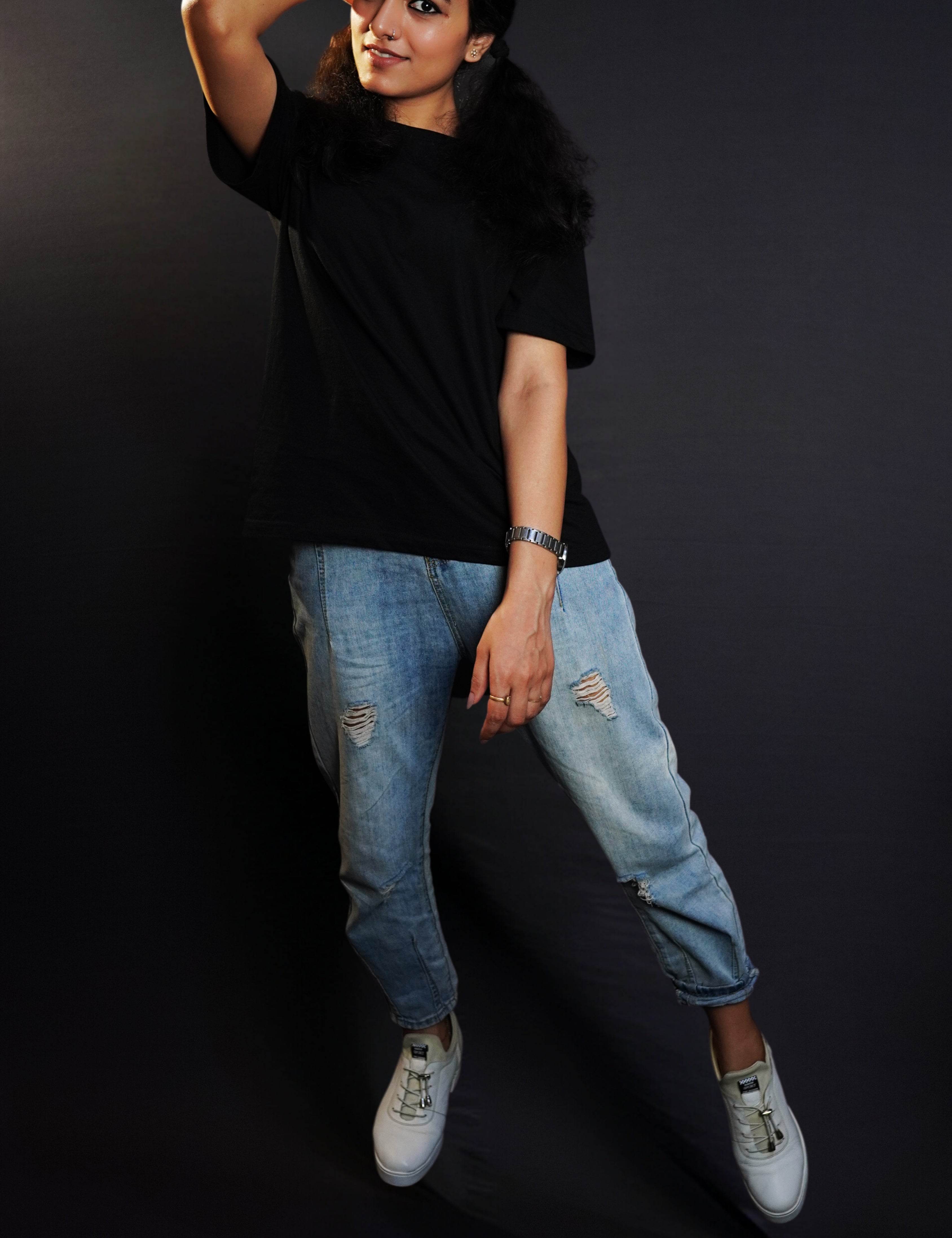 A stylish model wearing a plain short sleeved girl's cotton stretchable midnight black t-shirt, posing with her hand on the side of her head with elbow towards the camera, showcasing a fashionable snug fit-Muselot