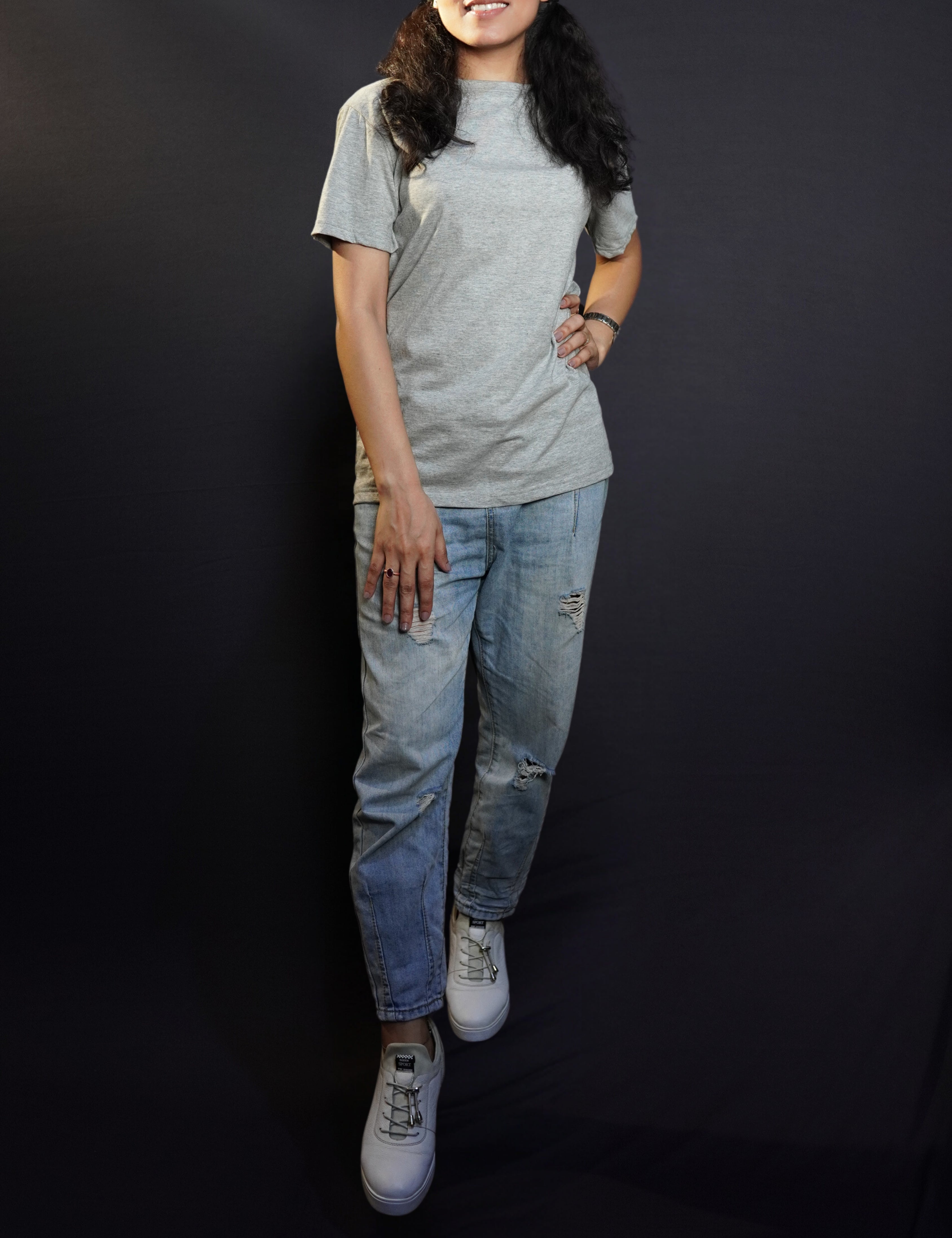 A stylish model posing with her hand on her waist and another on her thigh, wearing a women's plain short sleeved misty grey t-shirt, highlighting a unique voguish fit-Muselot