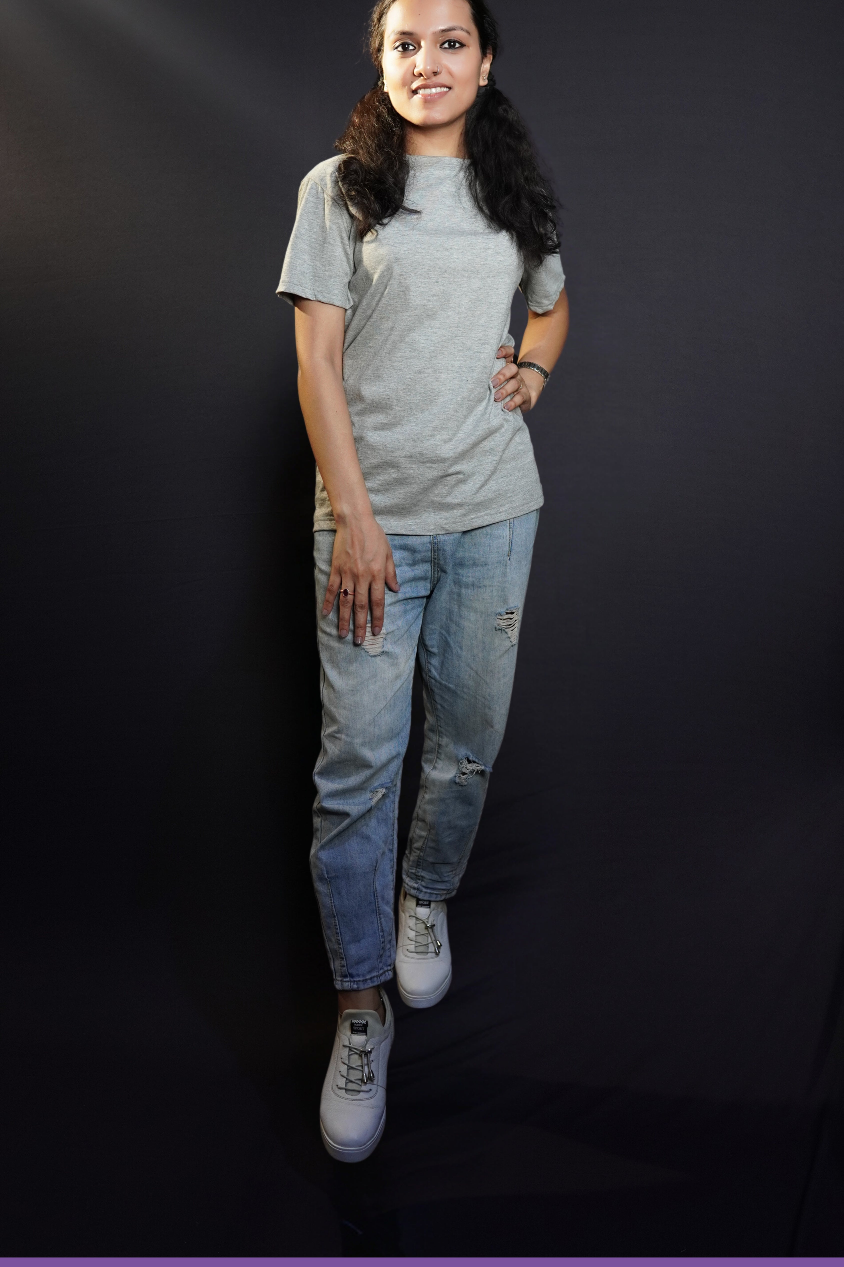 A stylish model posing with her hand on her waist and another on her thigh, wearing a women's plain short sleeved misty grey t-shirt, highlighting a unique voguish fit-Muselot