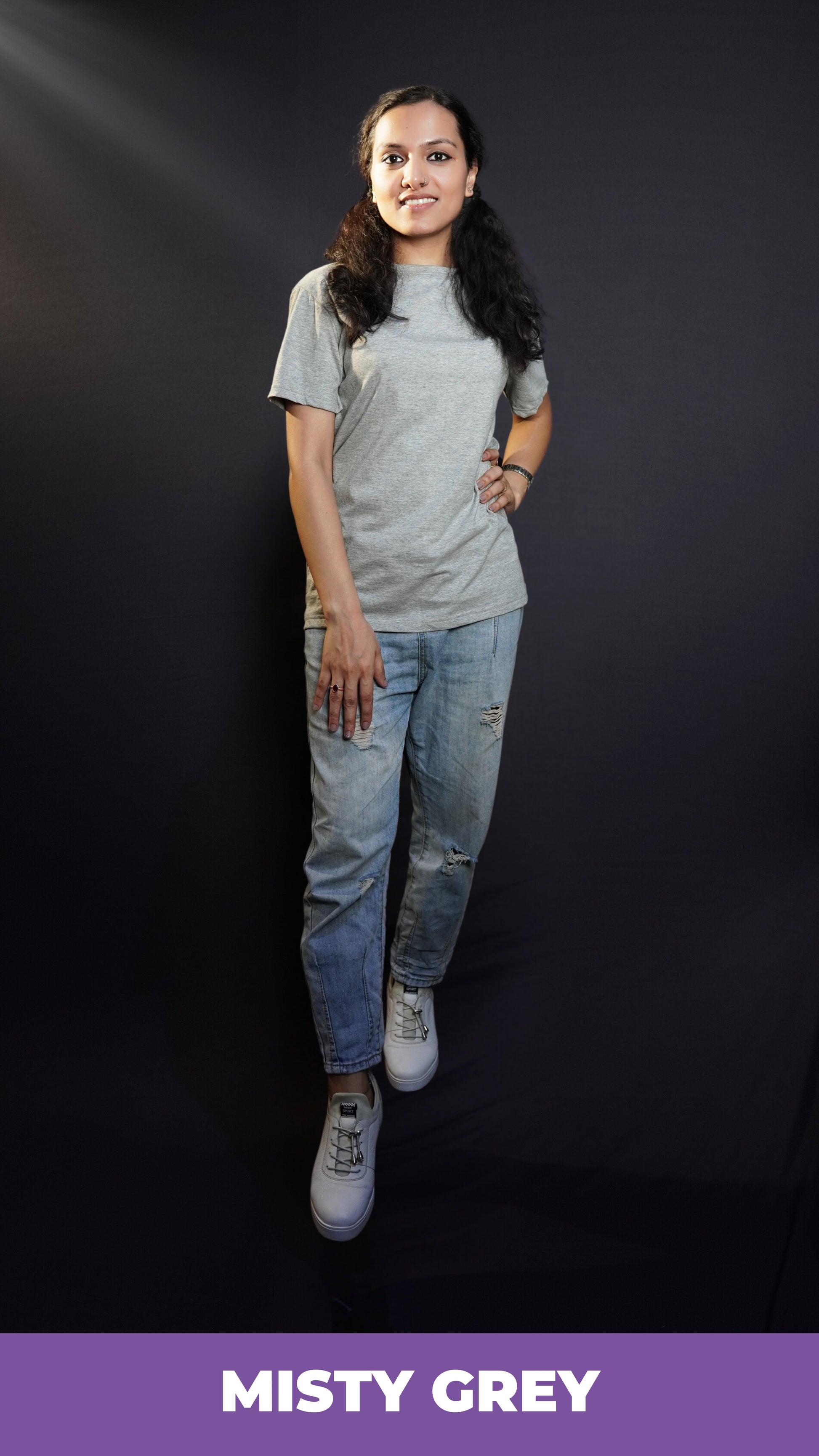 A stylish model posing with her hand on her waist and another on her thigh, wearing a women's plain short sleeved misty grey t-shirt, highlighting a unique voguish fit-Muselot