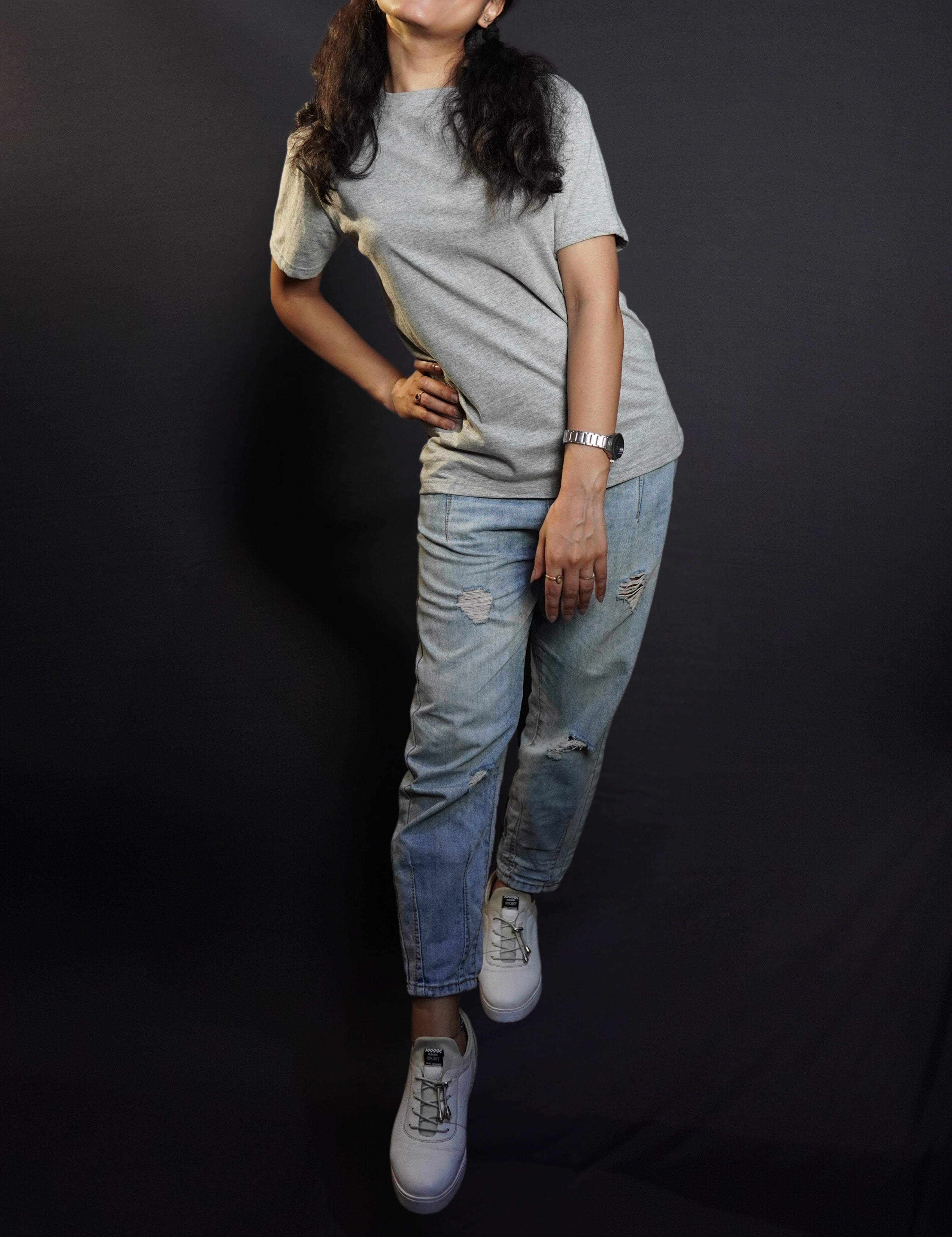 A cute woman wearing adult's round neck long length short sleeved misty grey t-shirt, posing with her hand on her waist as she sways to her side, highlighting a up to the minute easygoing fit-Muselot
