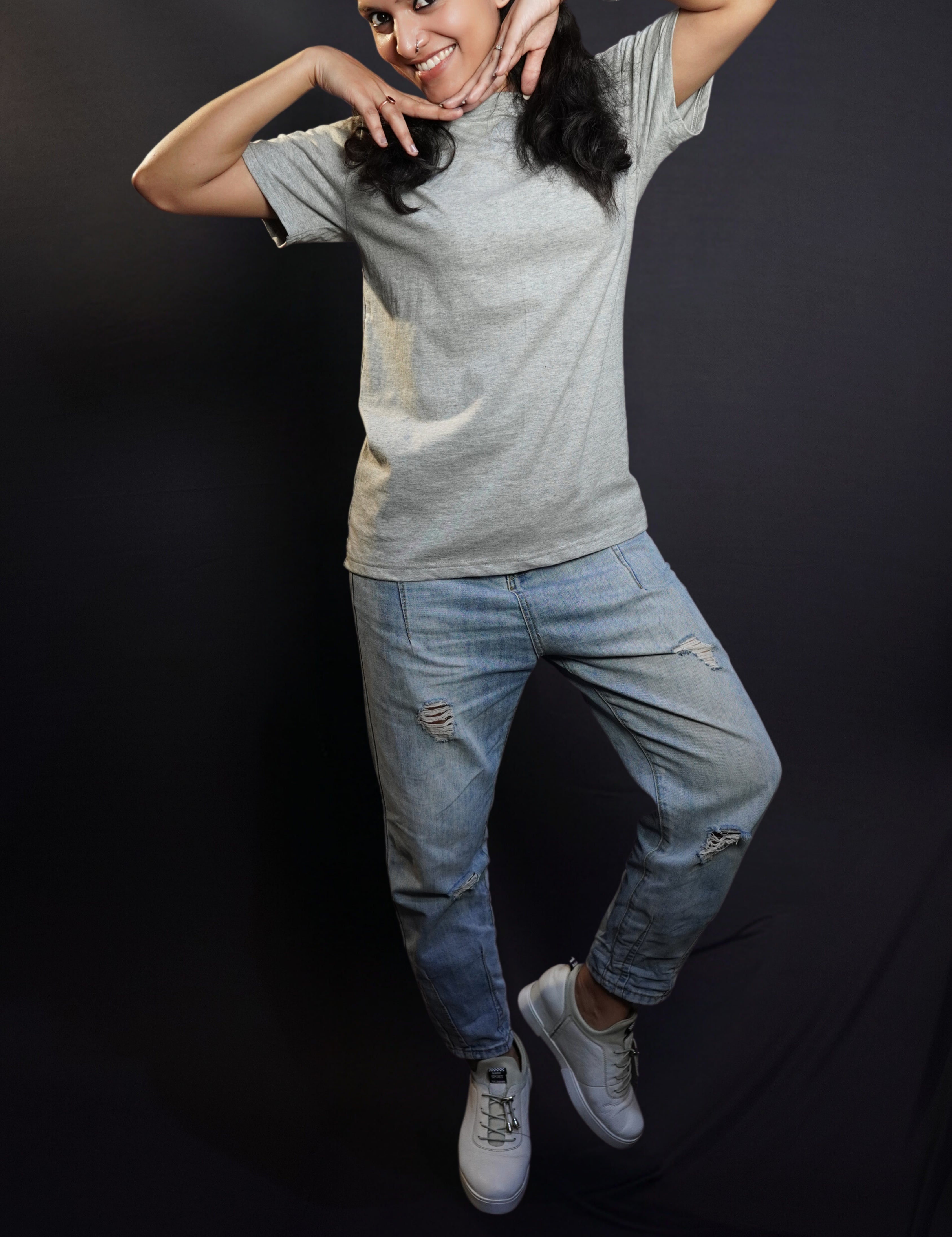 A woman posing happily with her hands under her chin, wearing a plain stretchable quick drying round neck misty grey plain t-shirt, highlighting a relaxed fashionable look-Muselot