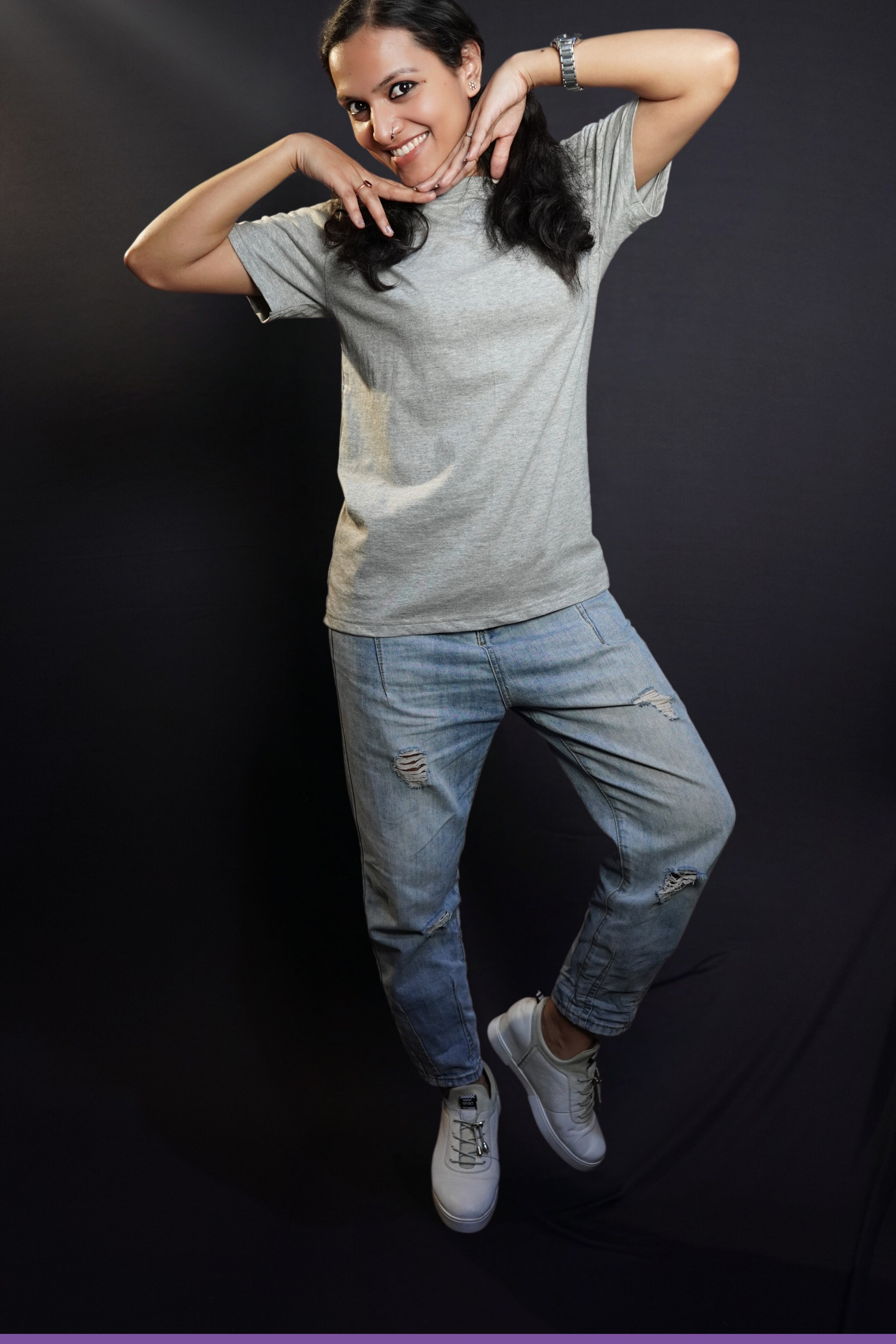 A woman posing happily with her hands under her chin, wearing a plain stretchable quick drying round neck misty grey plain t-shirt, highlighting a relaxed fashionable look-Muselot