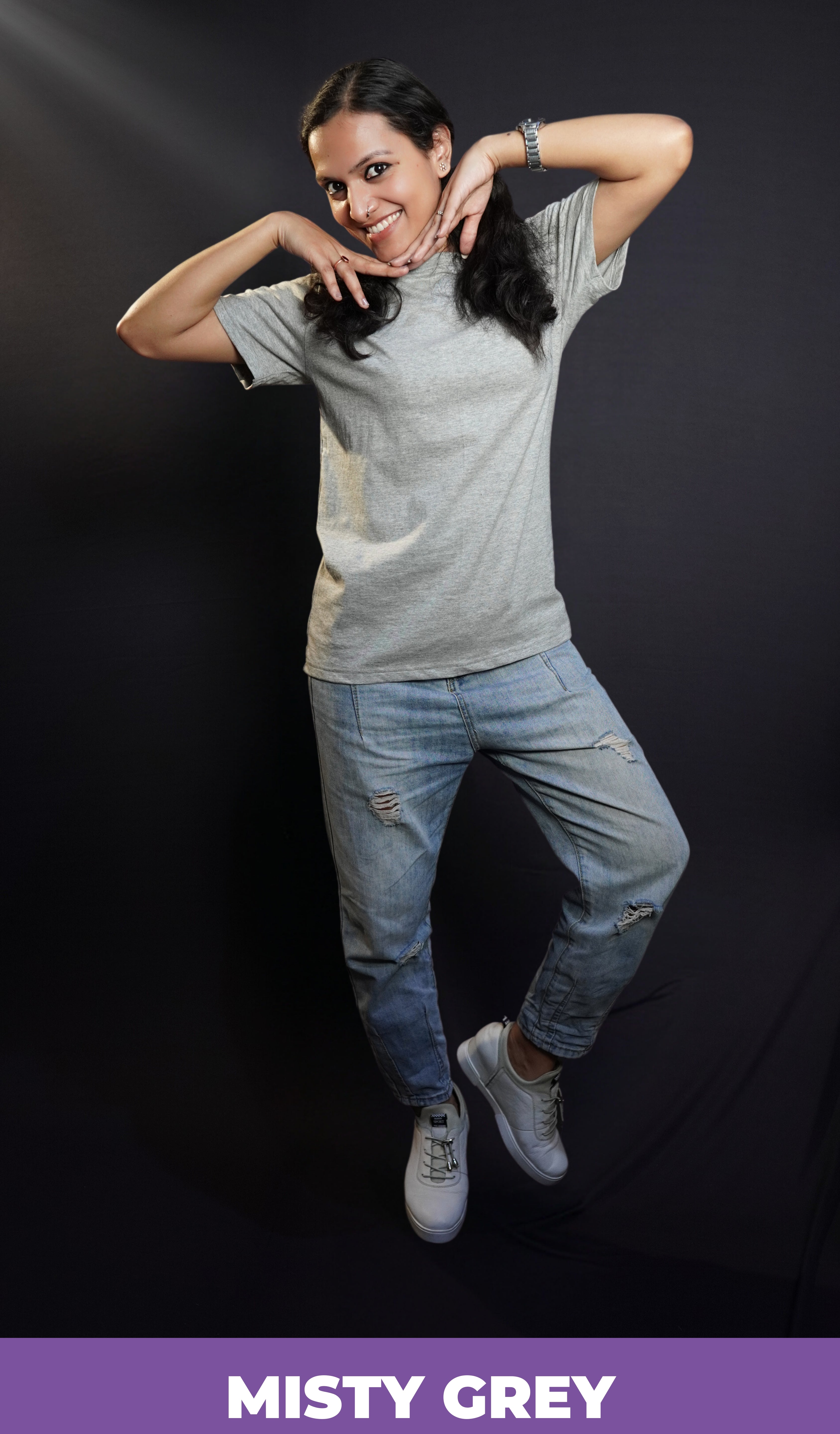 A woman posing happily with her hands under her chin, wearing a plain stretchable quick drying round neck misty grey plain t-shirt, highlighting a relaxed fashionable look-Muselot