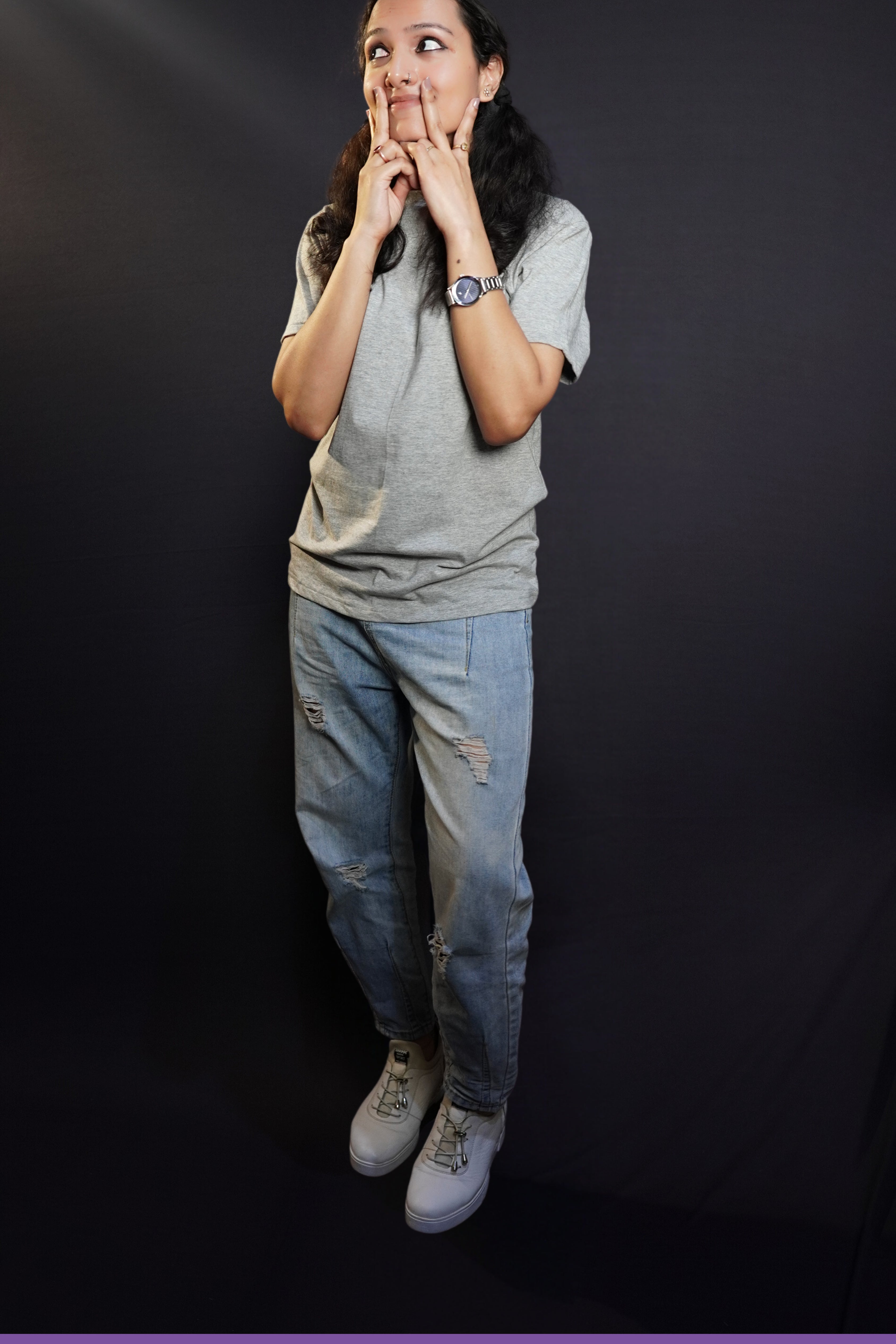 A woman wearing a long length round neck short sleeved plain t-shirt, posing with her hand on her cheeks making a v with her fingers, showcasing a soft homey fit-Muselot