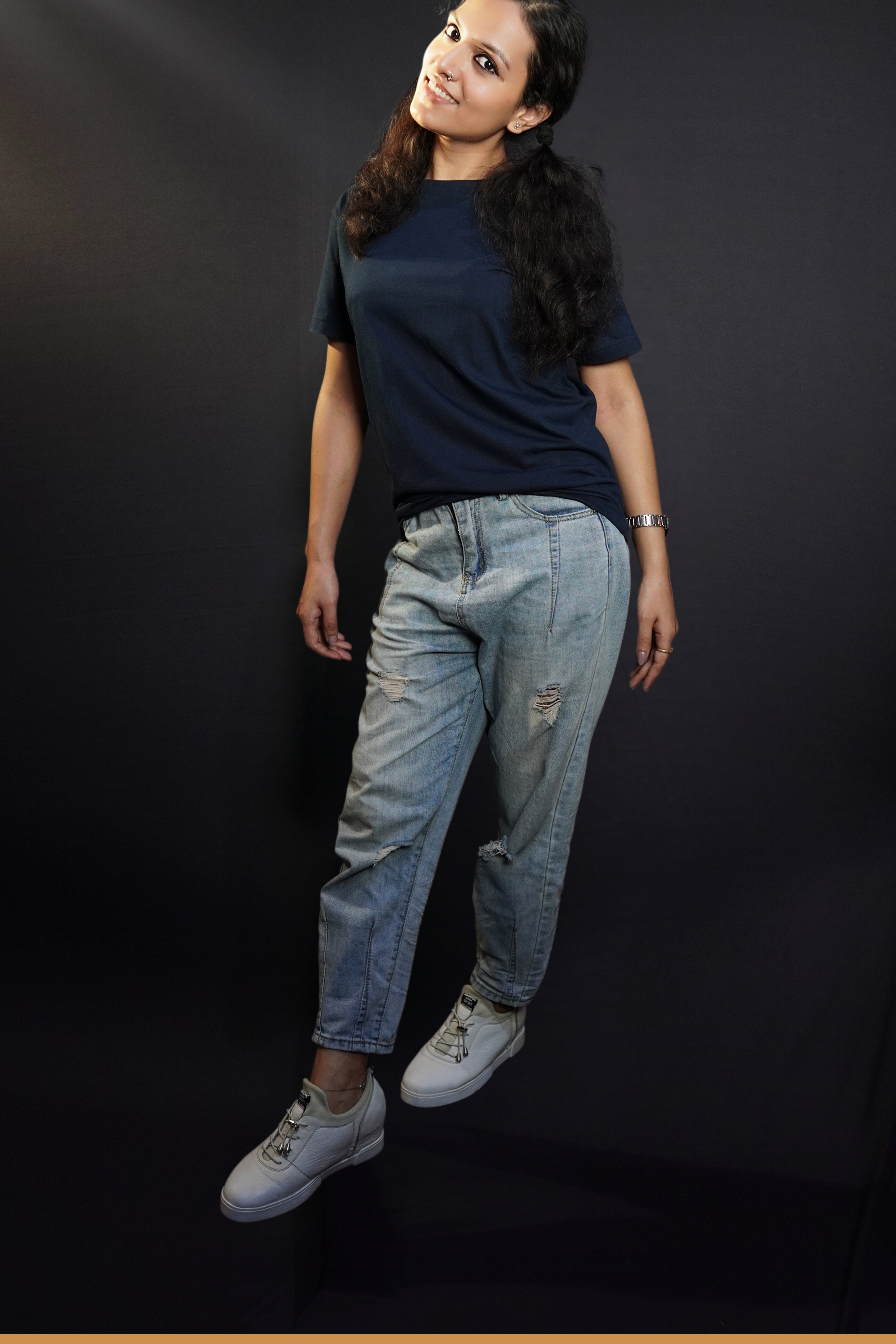 A woman wearing a girl's plain cotton round neck long length navy blue t-shirt, posing with her hands hanging on her sides, showcasing a popular relaxed fit-Muselot