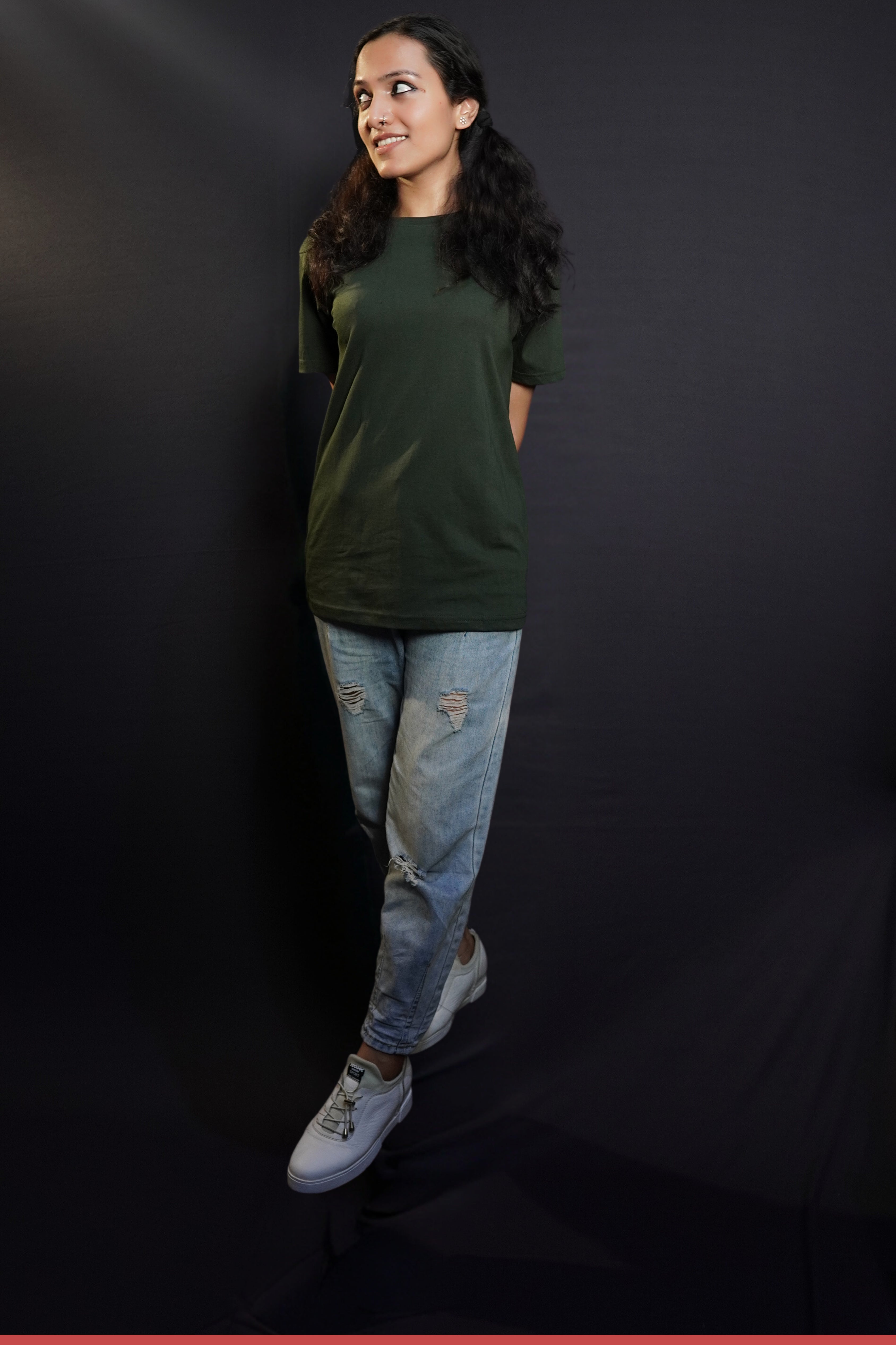 A woman wearing a women's cotton short sleeved olive green t-shirt, posing with her hands at her back as she stands slightly sideways, highlighting a relaxed casual fit-Muselot