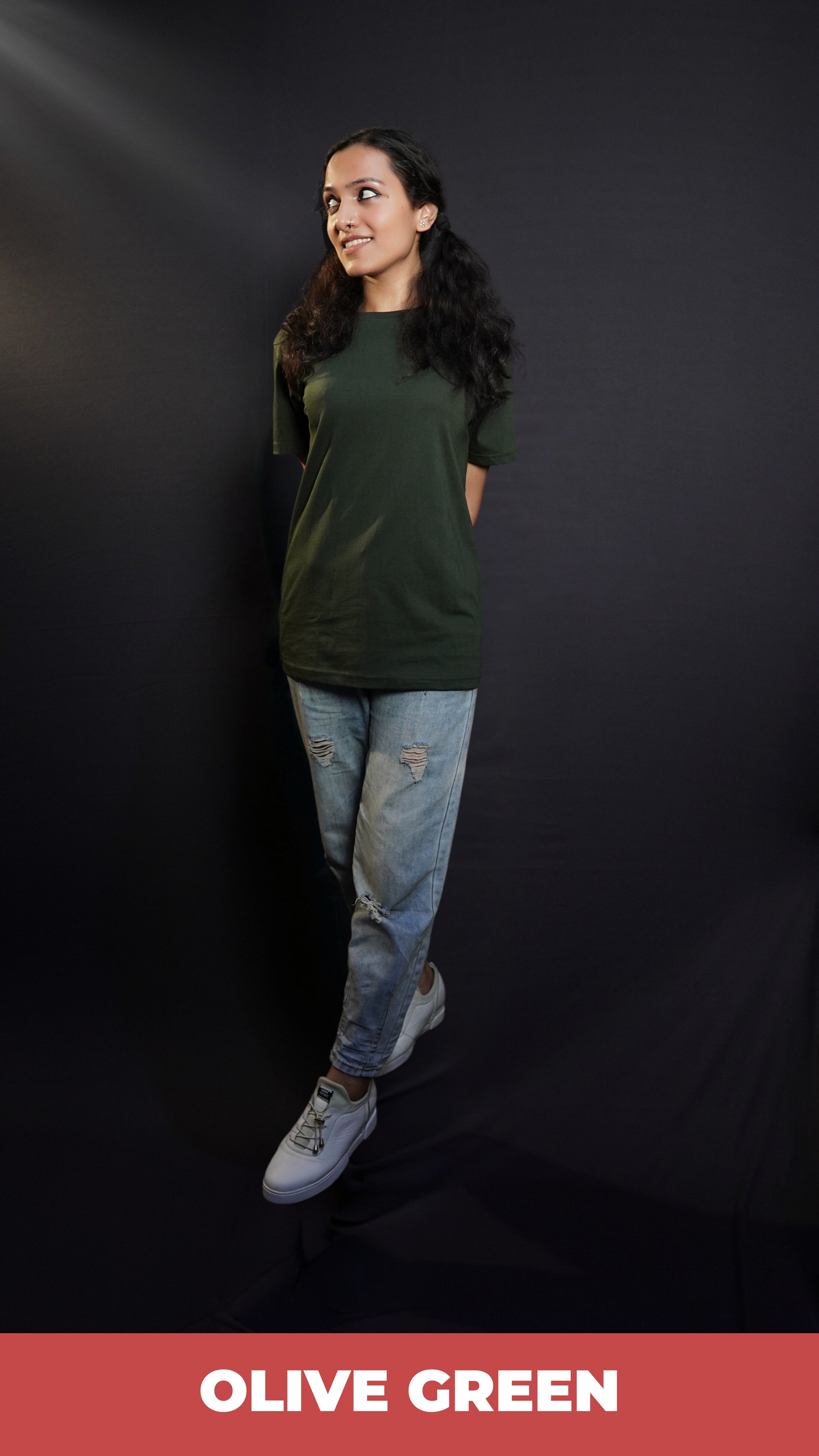 A woman wearing a women's cotton short sleeved olive green t-shirt, posing with her hands at her back as she stands slightly sideways, highlighting a relaxed casual fit-Muselot