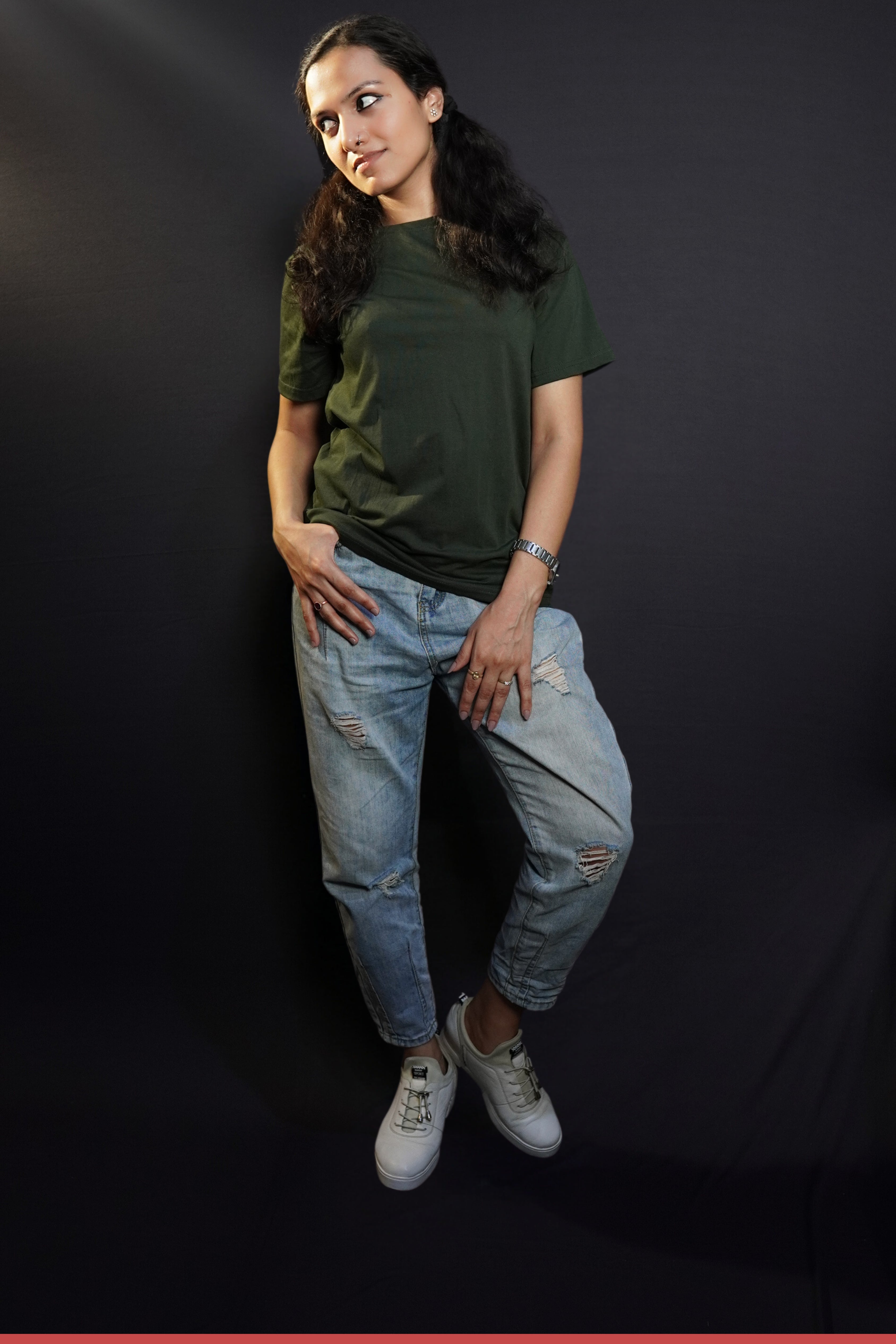 A woman posing with her hand on her pocket while she looks sideways, wearing a plain long length moisture wicking olive green t-shirt, showcasing an up to the minute loose fit-Muselot