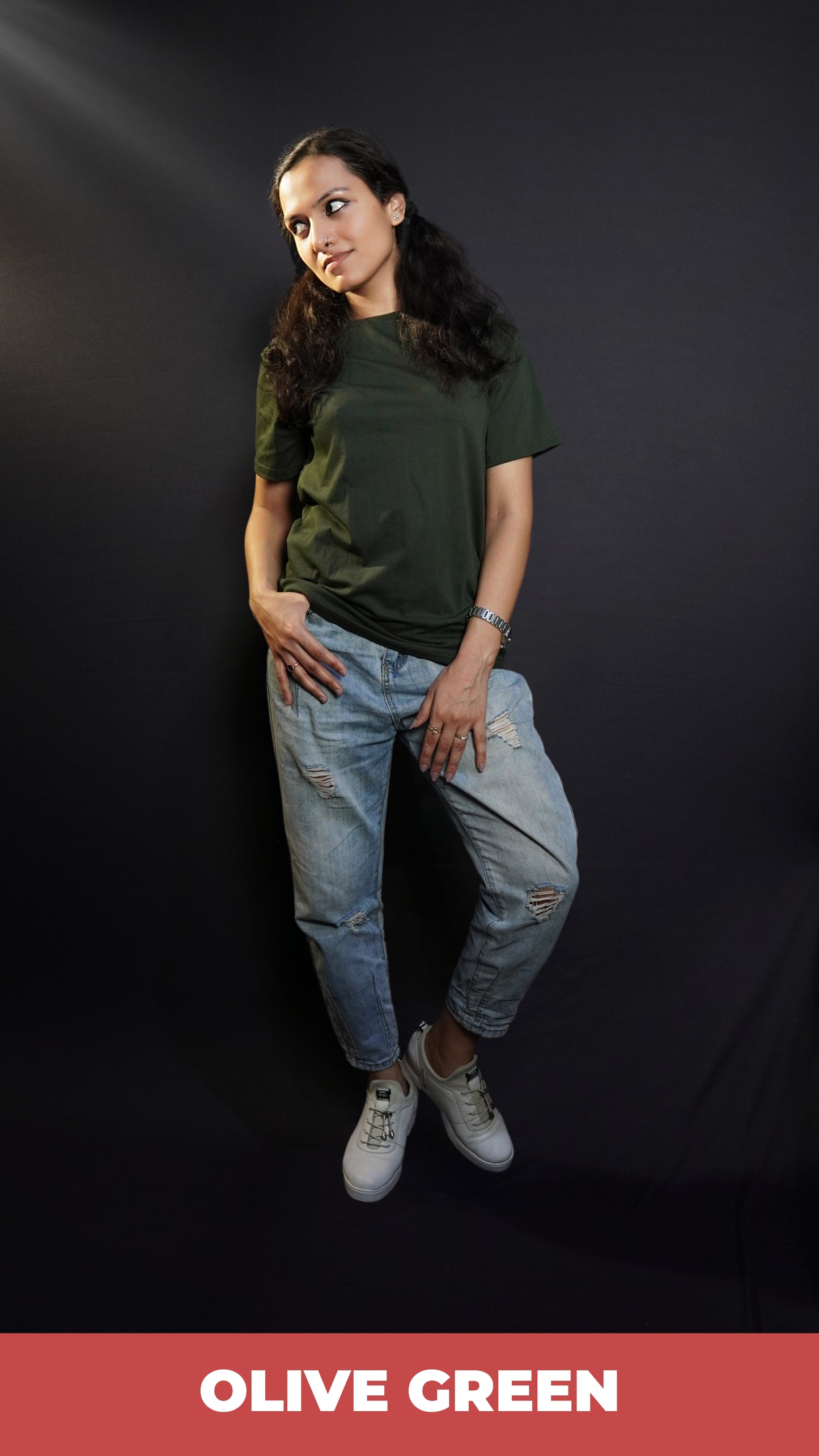 A woman posing with her hand on her pocket while she looks sideways, wearing a plain long length moisture wicking olive green t-shirt, showcasing an up to the minute loose fit-Muselot