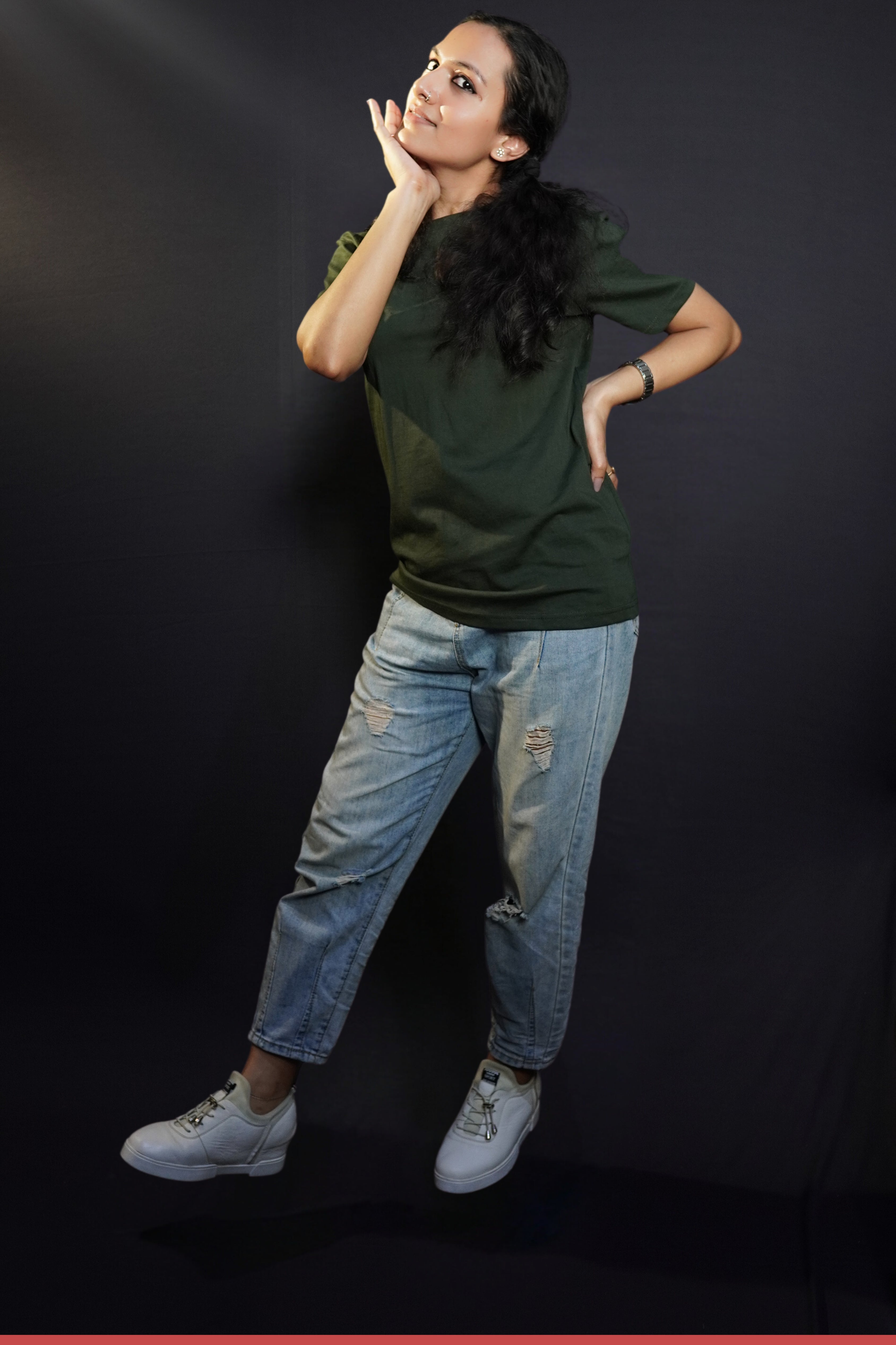 A woman with her hand under her chin and other on her waist, wearing a plus size short sleeved quick drying olive green t-shirt, highlighting an in demand baggy fit-Muselot