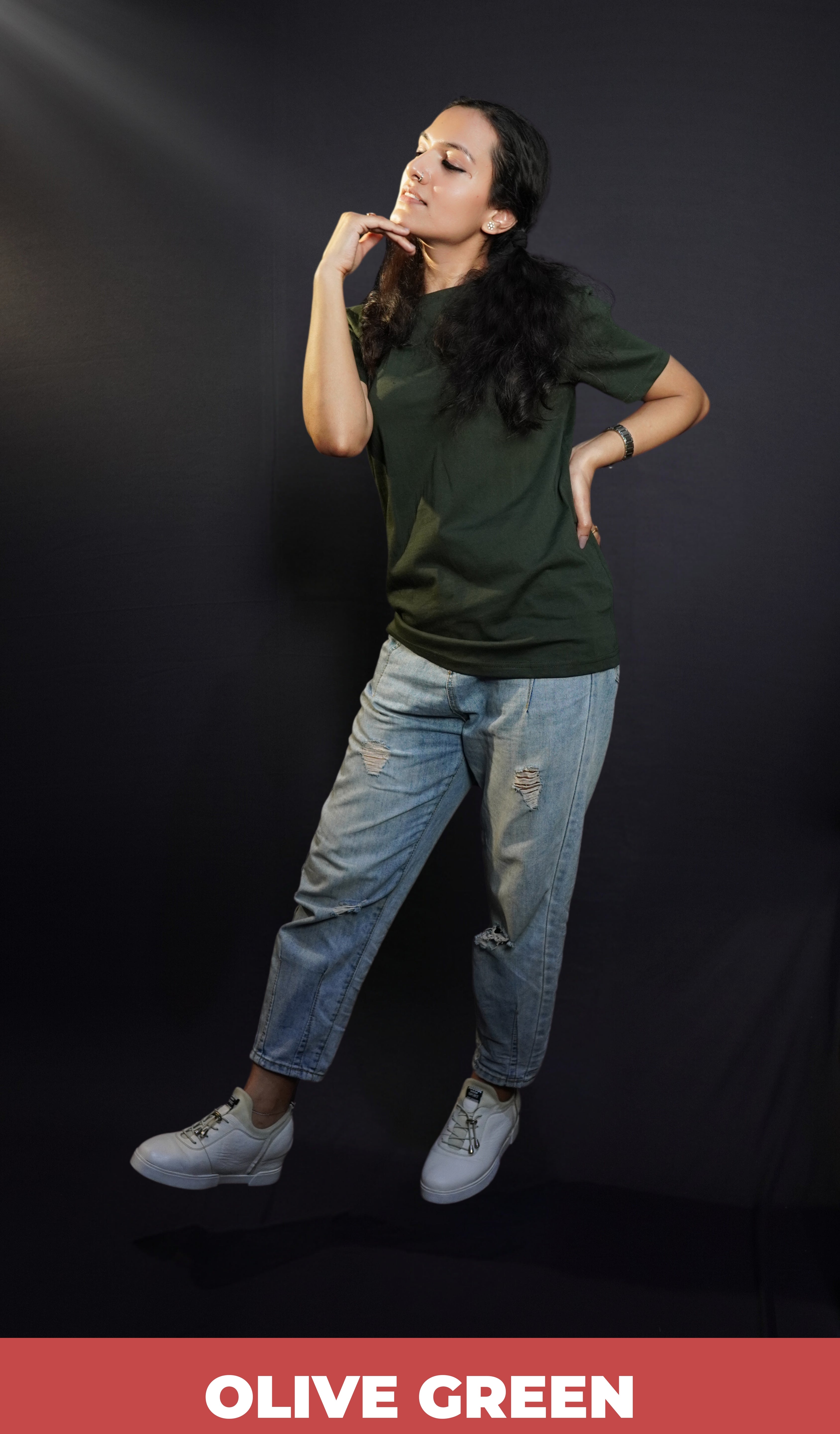A woman posing with her hand under her chin and other on her waist, wearing a girl's plain stretchable round neck olive green t-shirt, showcasing a popular perfect fit-Muselot