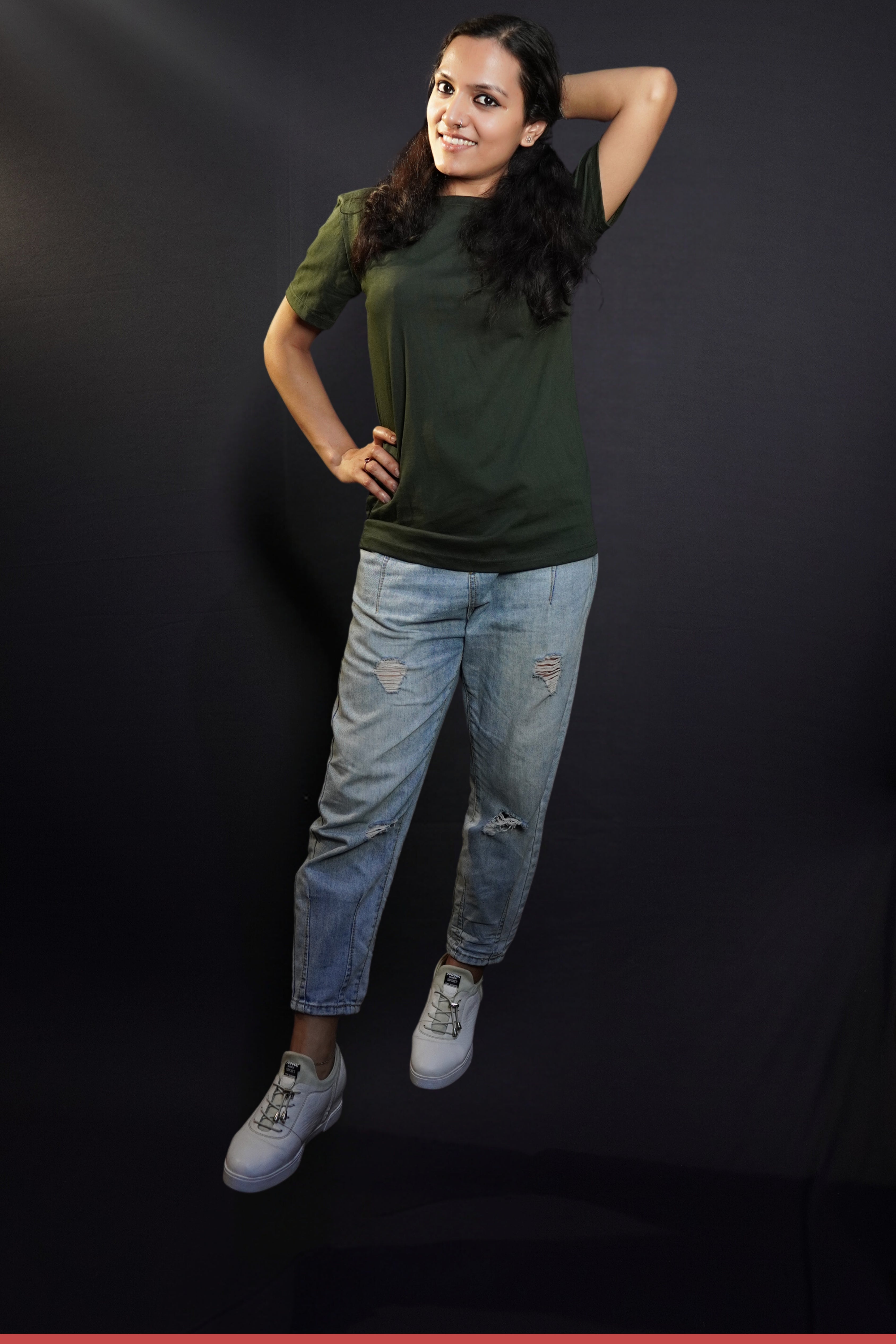 A woman wearing men's plain long length summer olive green t-shirt, posing with her hand up behind her head and other on her waist, highlighting a modern voguish look-Muselot
