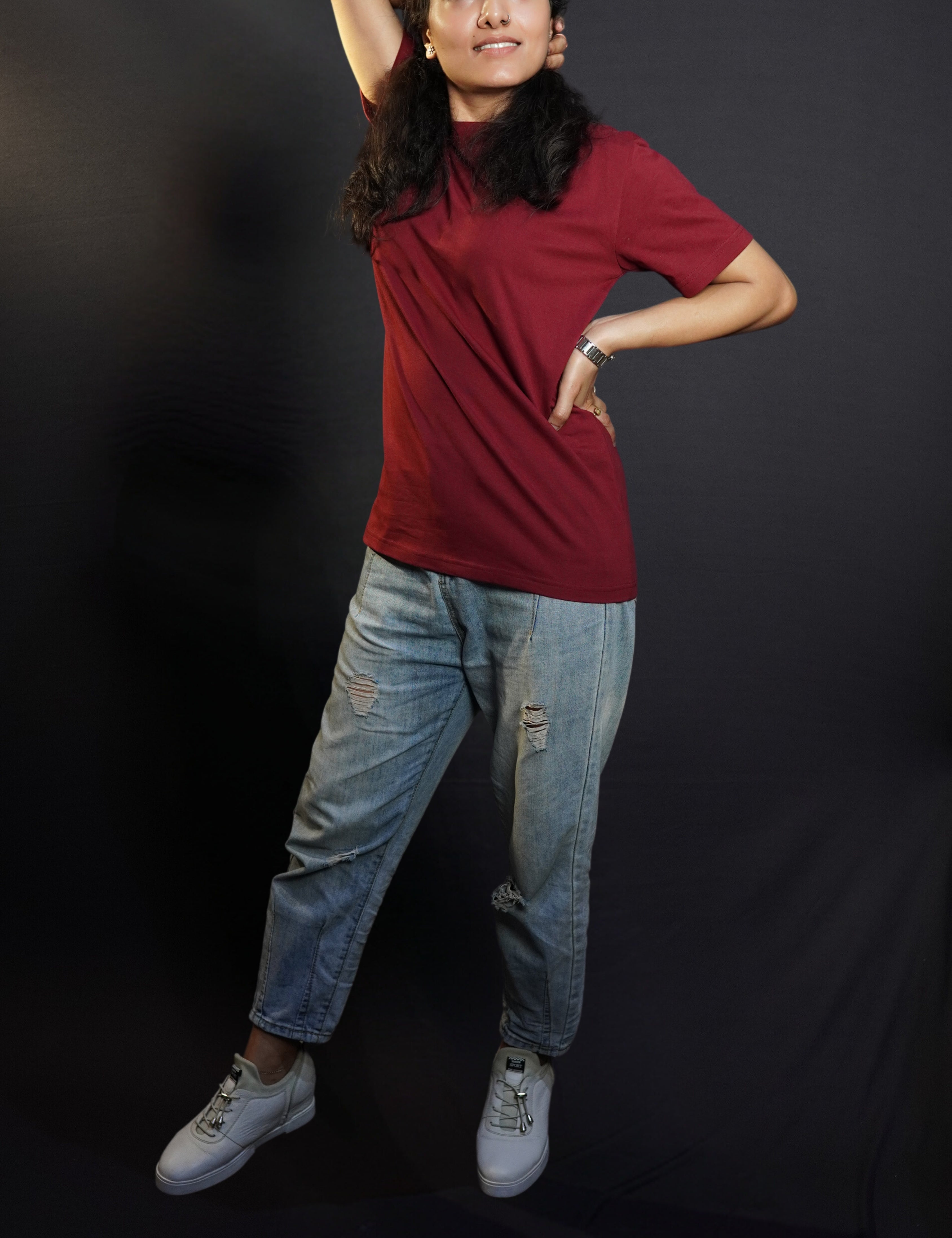 A woman posing with her hand up and behind her head and another on her waist, wearing a long length short sleeved moisture wicking rich maroon t-shirt, showcasing a loose flowing fit-Muselot