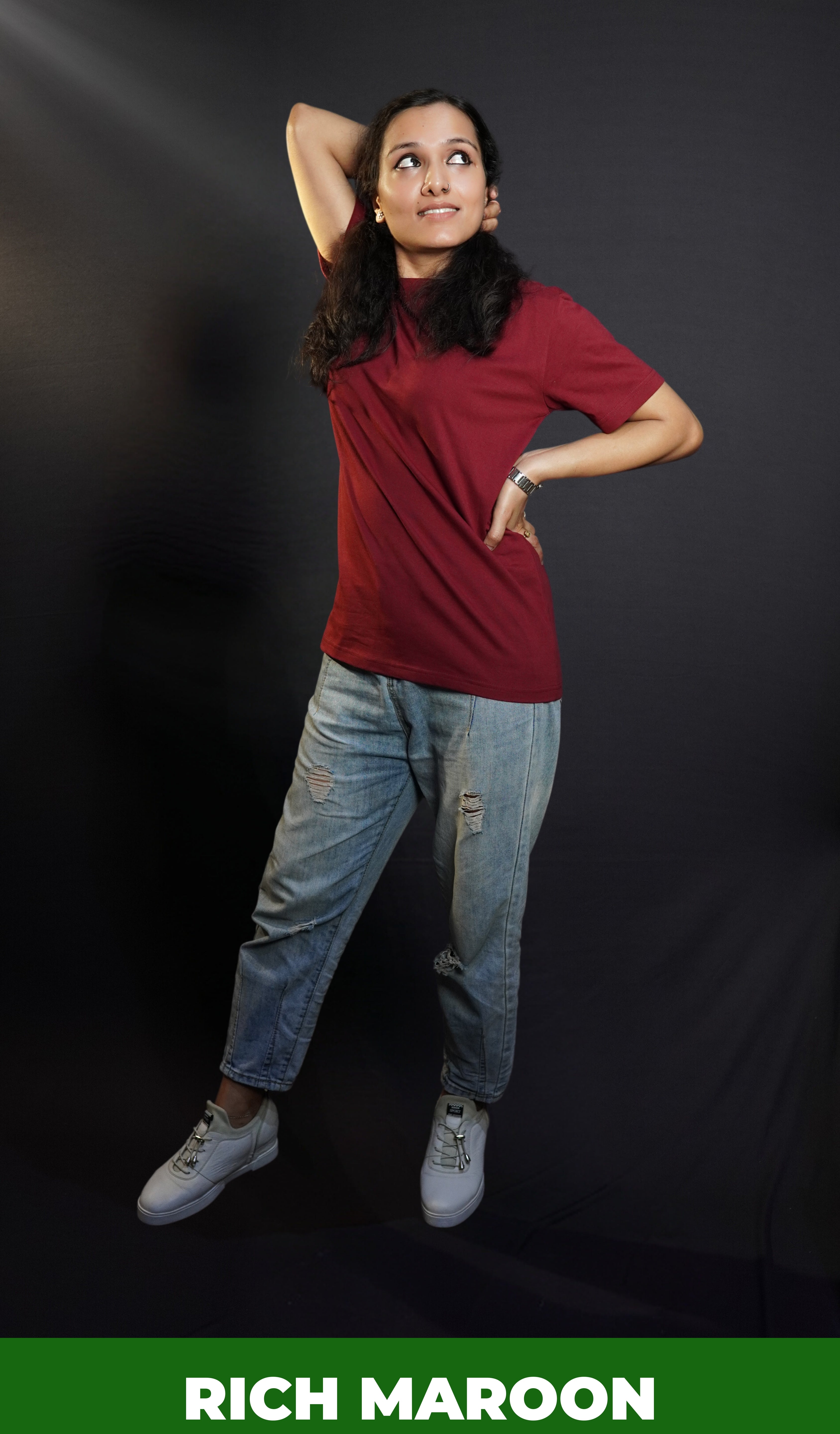 A woman posing with her hand up and behind her head and another on her waist, wearing a long length short sleeved moisture wicking rich maroon t-shirt, showcasing a loose flowing fit-Muselot