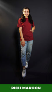 A stylish model wearing a unisex round neck stretchable rich maroon t-shirt, posing with her hand on her waist and other on her thigh, showcasing a trendy snug fit-Muselot