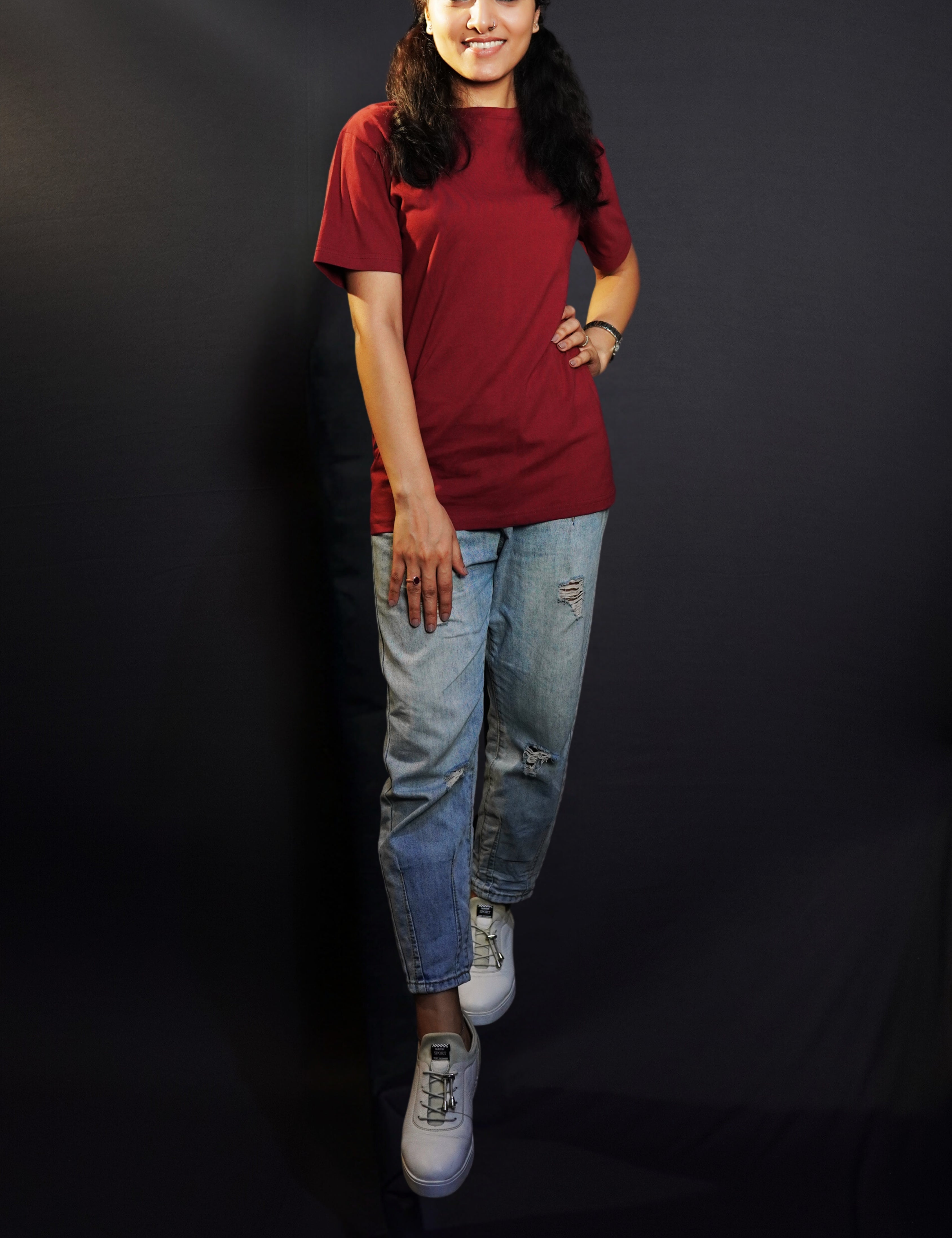 A stylish model wearing a unisex round neck stretchable rich maroon t-shirt, posing with her hand on her waist and other on her thigh, showcasing a trendy snug fit-Muselot