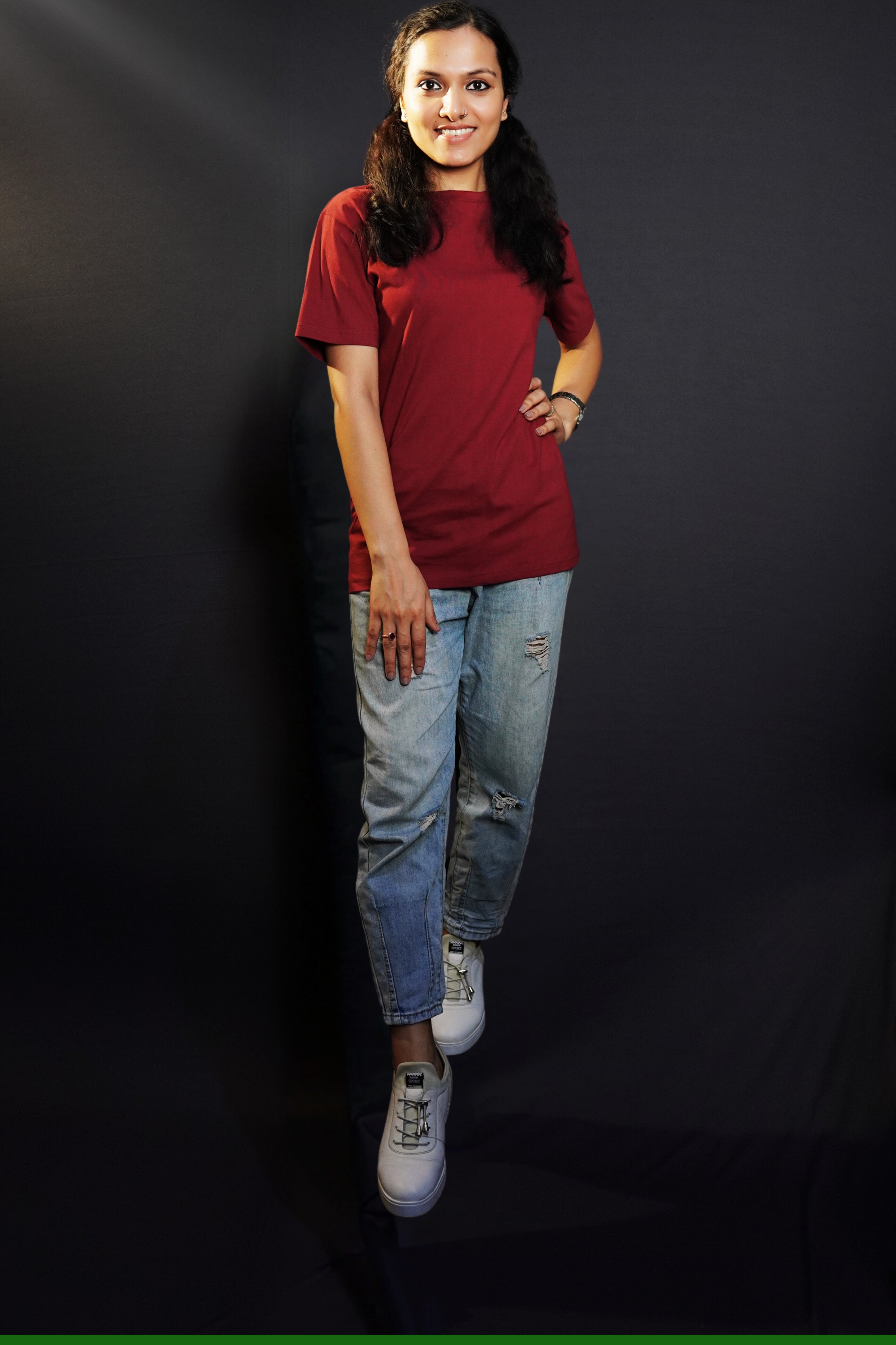 A stylish model wearing a unisex round neck stretchable rich maroon t-shirt, posing with her hand on her waist and other on her thigh, showcasing a trendy snug fit-Muselot