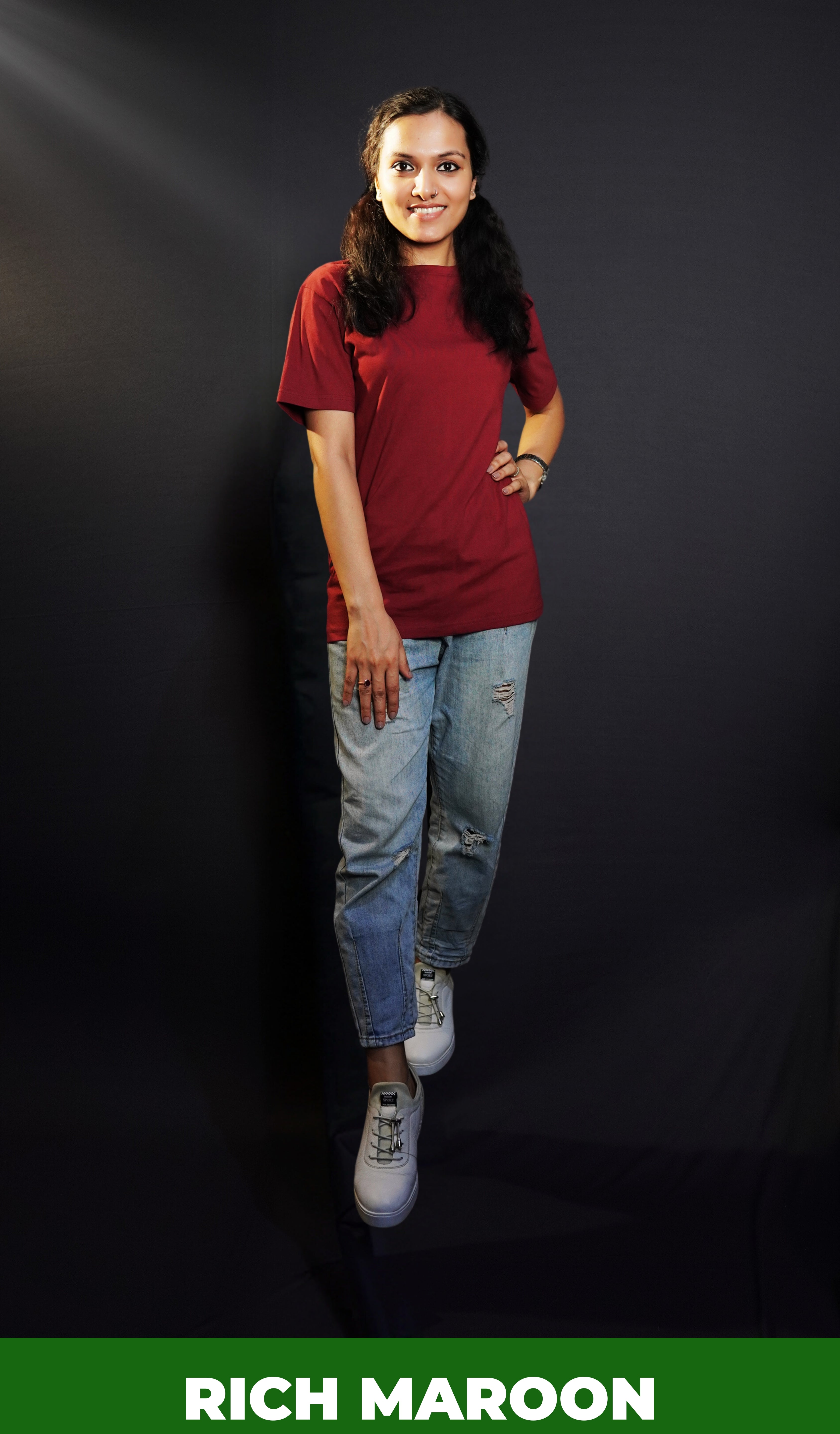 A stylish model wearing a unisex round neck stretchable rich maroon t-shirt, posing with her hand on her waist and other on her thigh, showcasing a trendy snug fit-Muselot