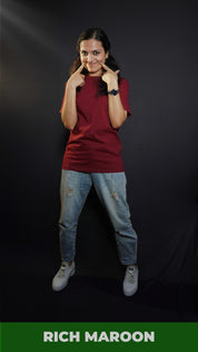 A woman smiling as her fingers poke into her cheeks, wearing a women's long length summer rich maroon t-shirt, showcasing a fashionable stylish look-Muselot