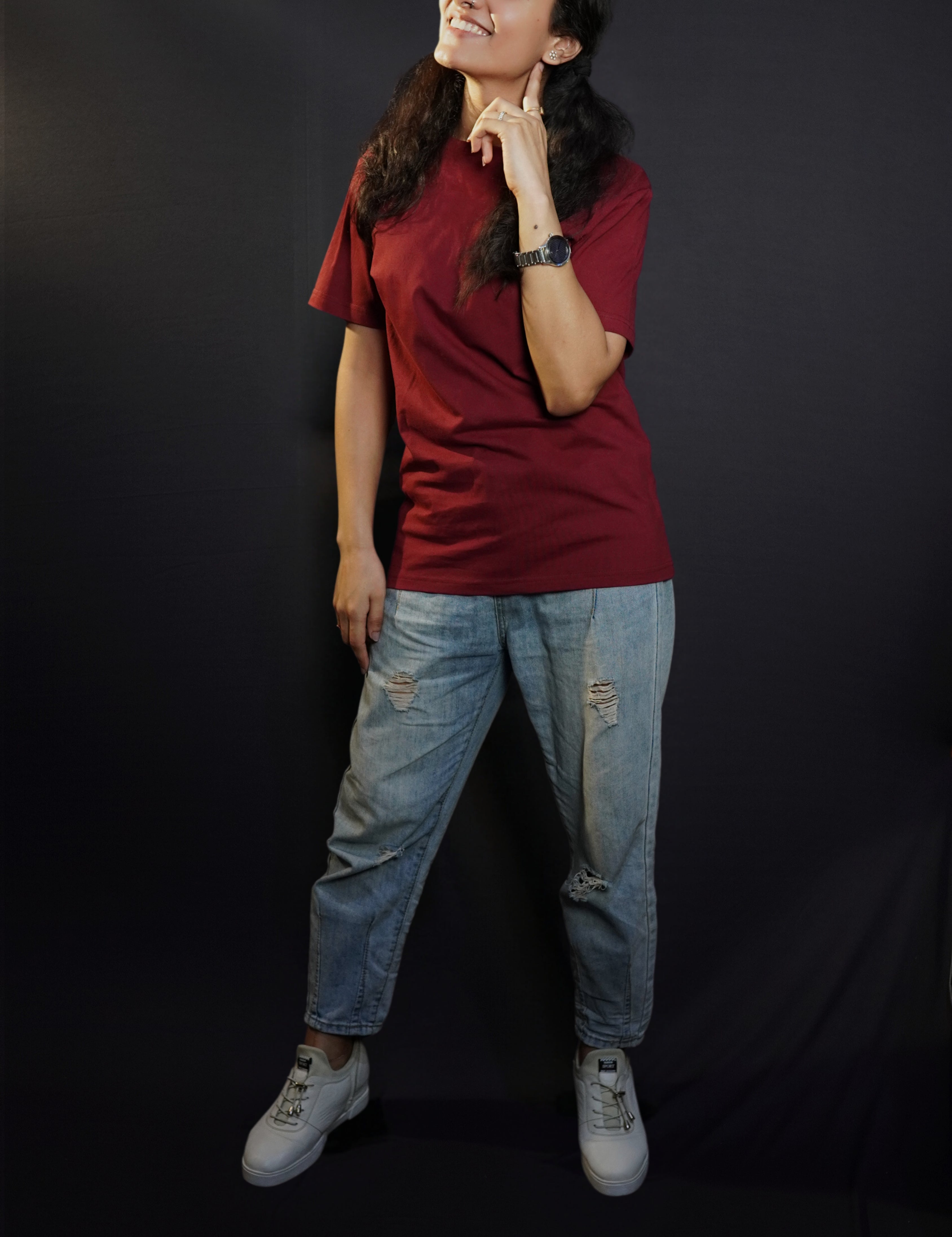 A woman wearing a girl's round neck stretchable rich maroon t-shirt, posing with her finger under her ear and other hanging on her side, showcasing a cool cozy look-Muselot