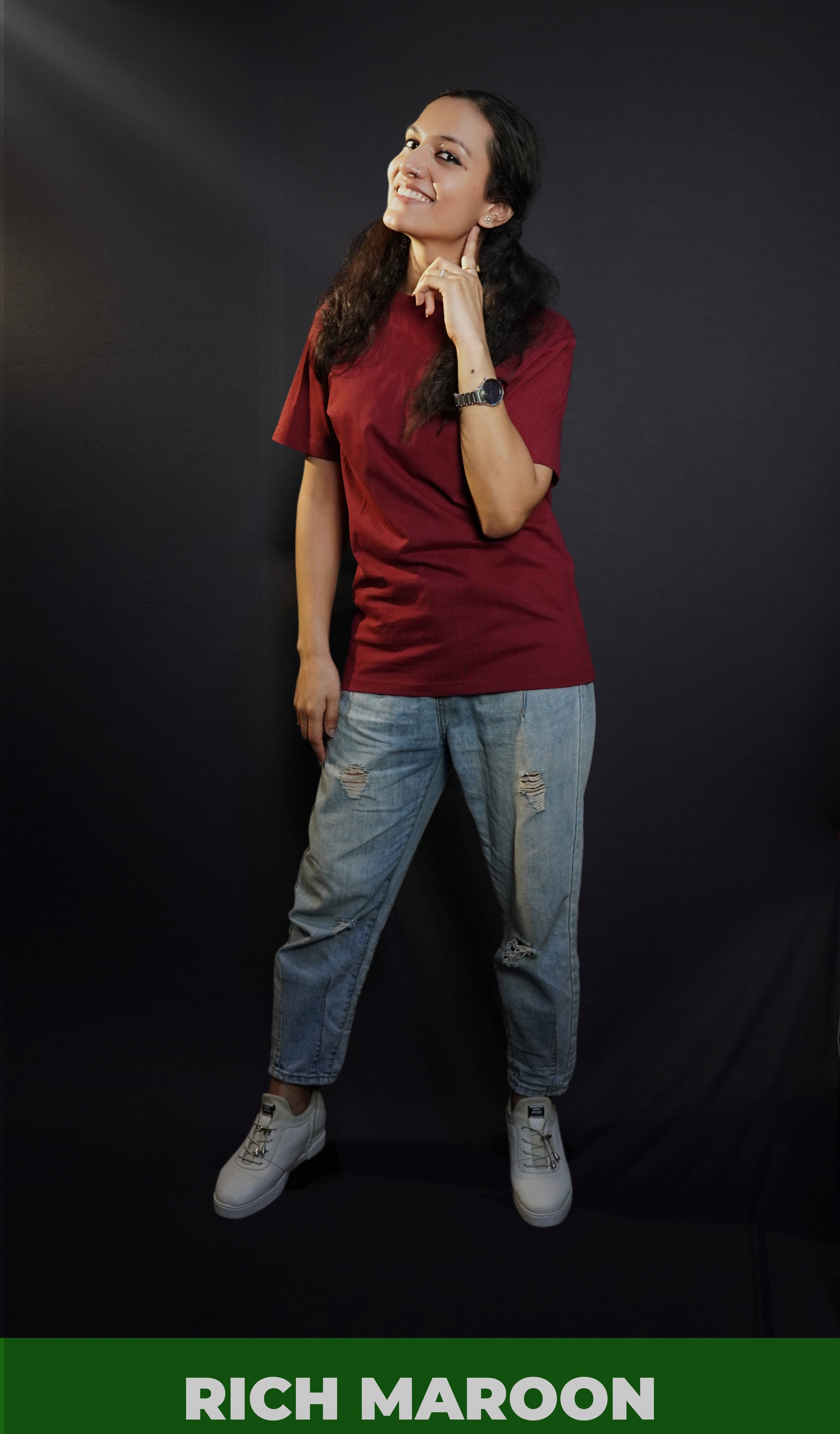 A woman wearing a girl's round neck stretchable rich maroon t-shirt, posing with her finger under her ear and other hanging on her side, showcasing a cool cozy look-Muselot