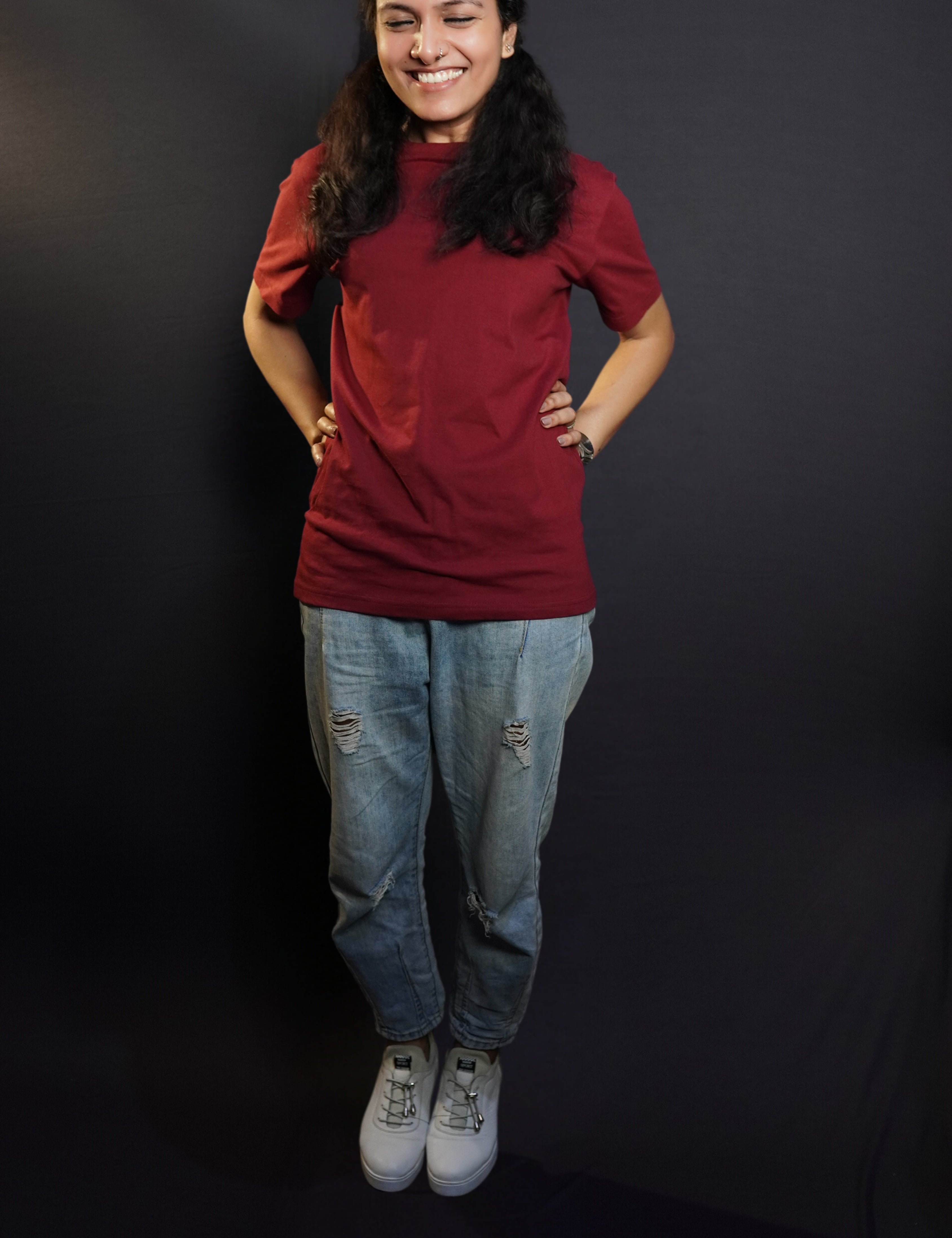 A woman laughing hard posing with her hands on her waist, wearing a short sleeved quick drying round neck rich maroon t-shirt, showcasing a modish in vogue look-Muselot