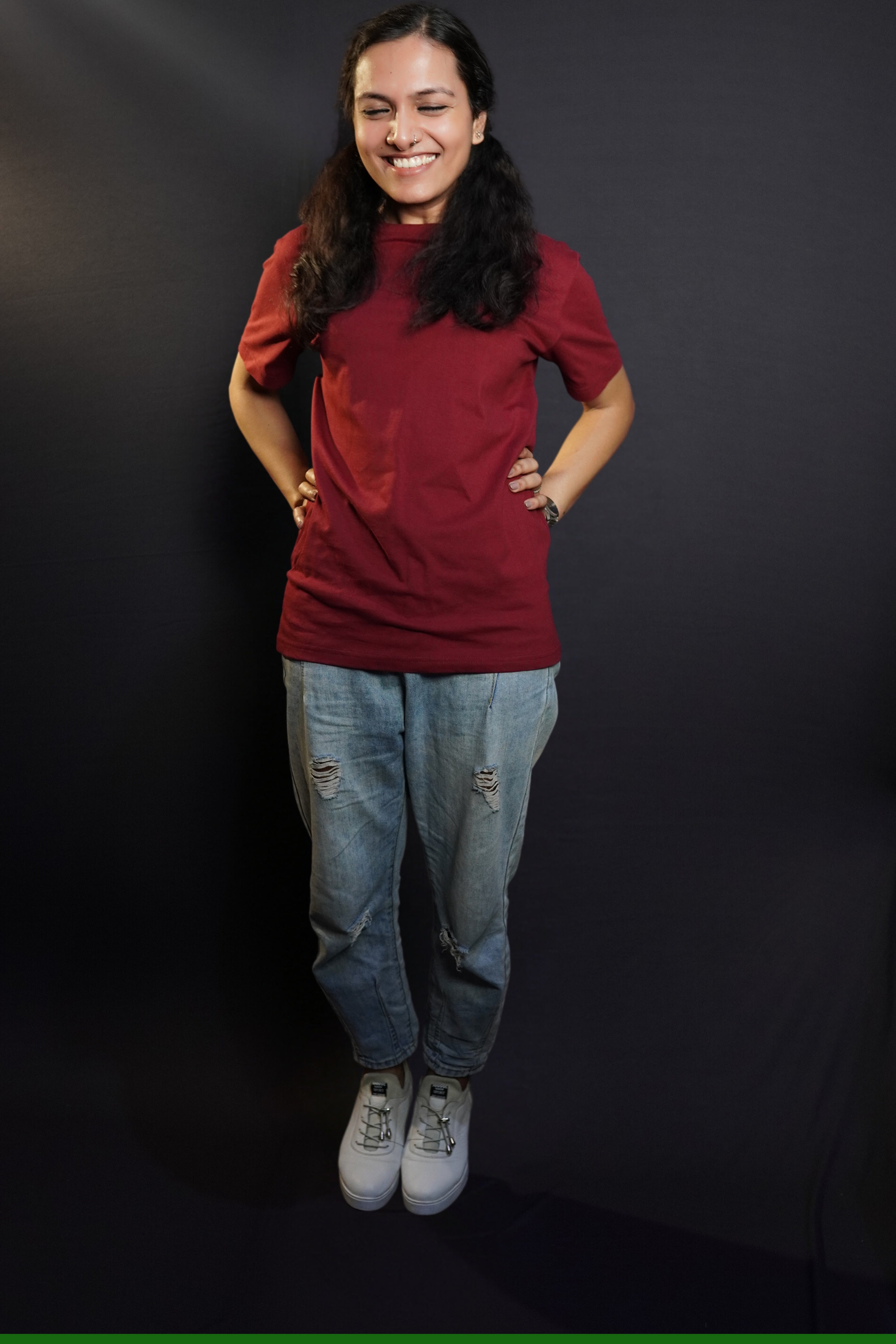 A woman laughing hard posing with her hands on her waist, wearing a short sleeved quick drying round neck rich maroon t-shirt, showcasing a modish in vogue look-Muselot