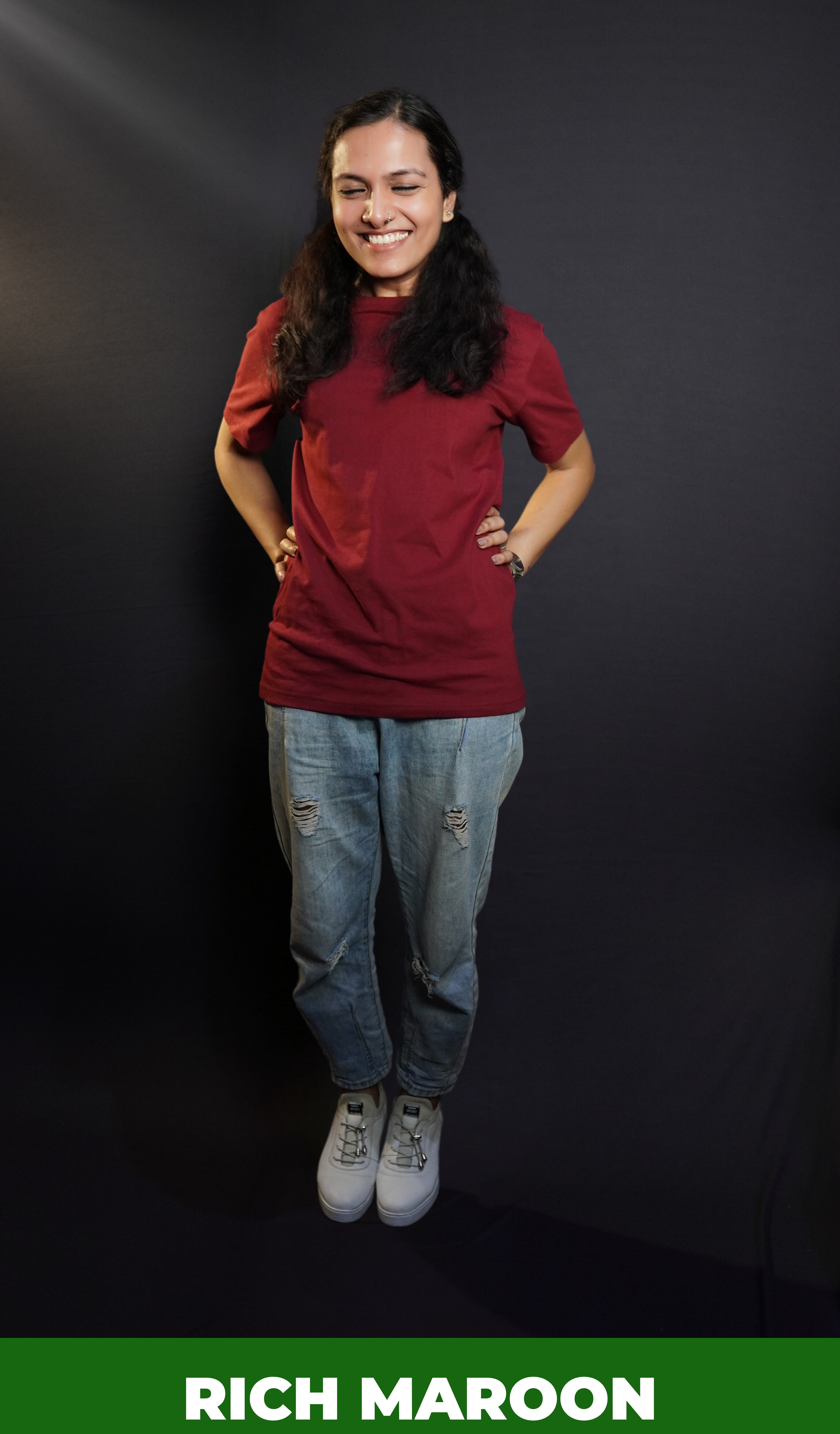 A woman laughing hard posing with her hands on her waist, wearing a short sleeved quick drying round neck rich maroon t-shirt, showcasing a modish in vogue look-Muselot