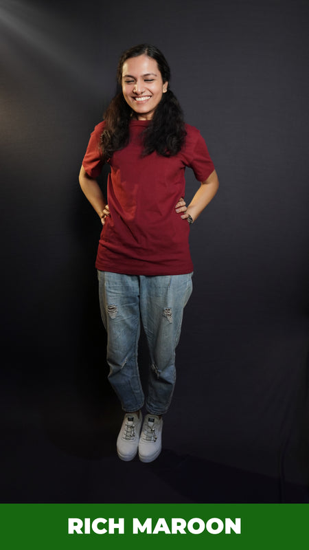 A woman laughing hard posing with her hands on her waist, wearing a short sleeved quick drying round neck rich maroon t-shirt, showcasing a modish in vogue look-Muselot