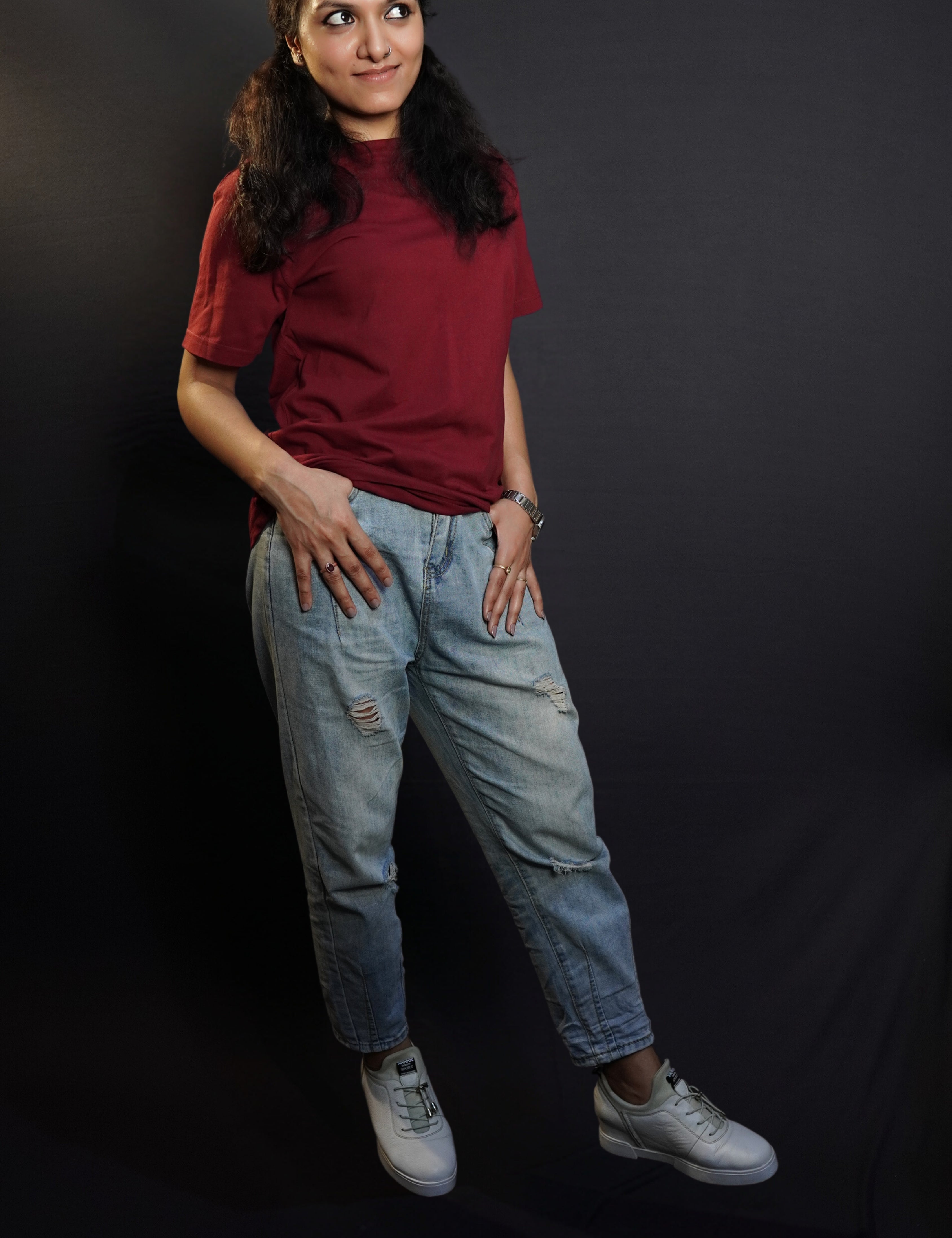 A woman wearing a short sleeved cotton stretchable rich maroon t-shirt, posing with her thumb inside the front pockets of her jeans, highlighting a stylish relaxed fit-Muselot