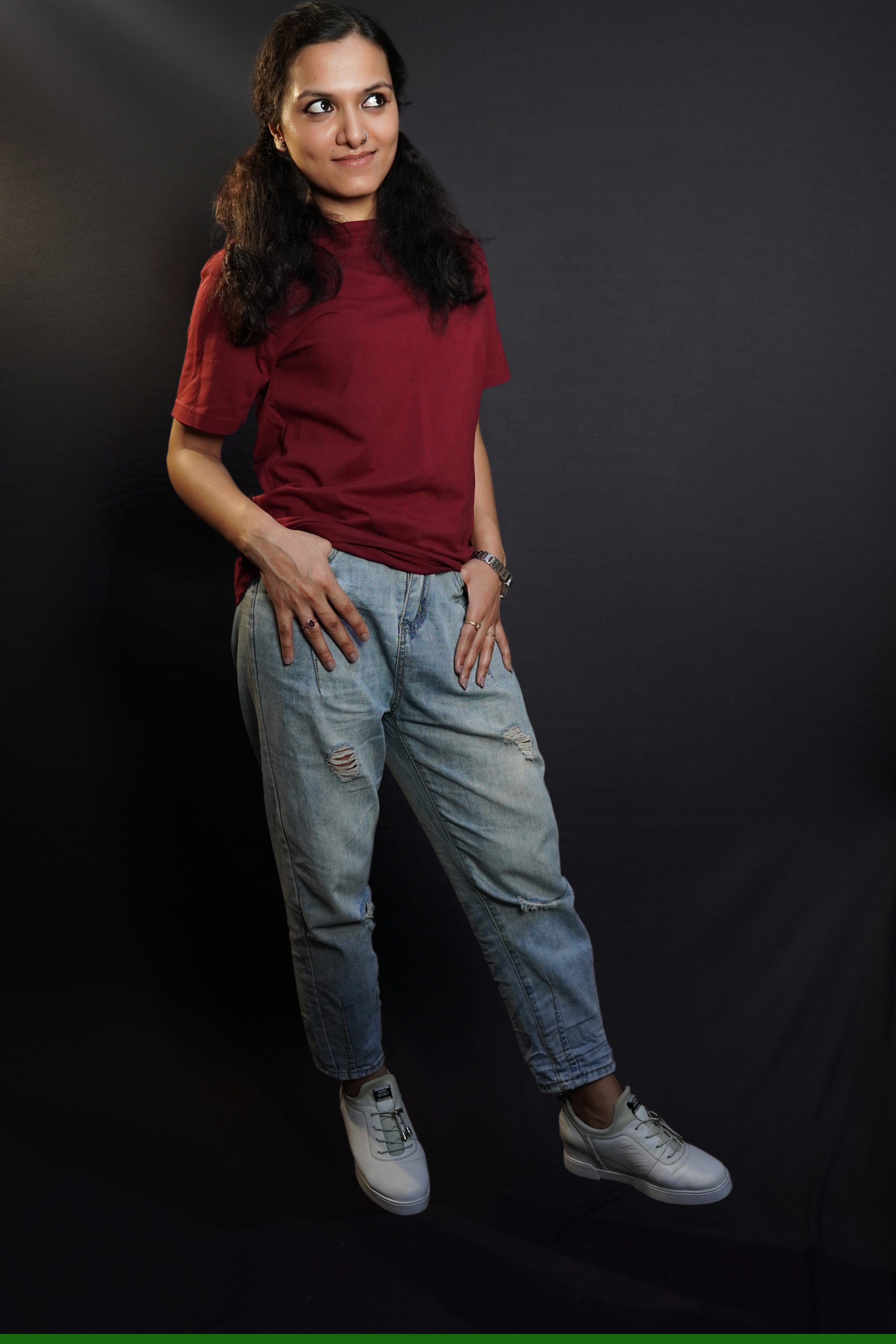 A woman wearing a short sleeved cotton stretchable rich maroon t-shirt, posing with her thumb inside the front pockets of her jeans, highlighting a stylish relaxed fit-Muselot