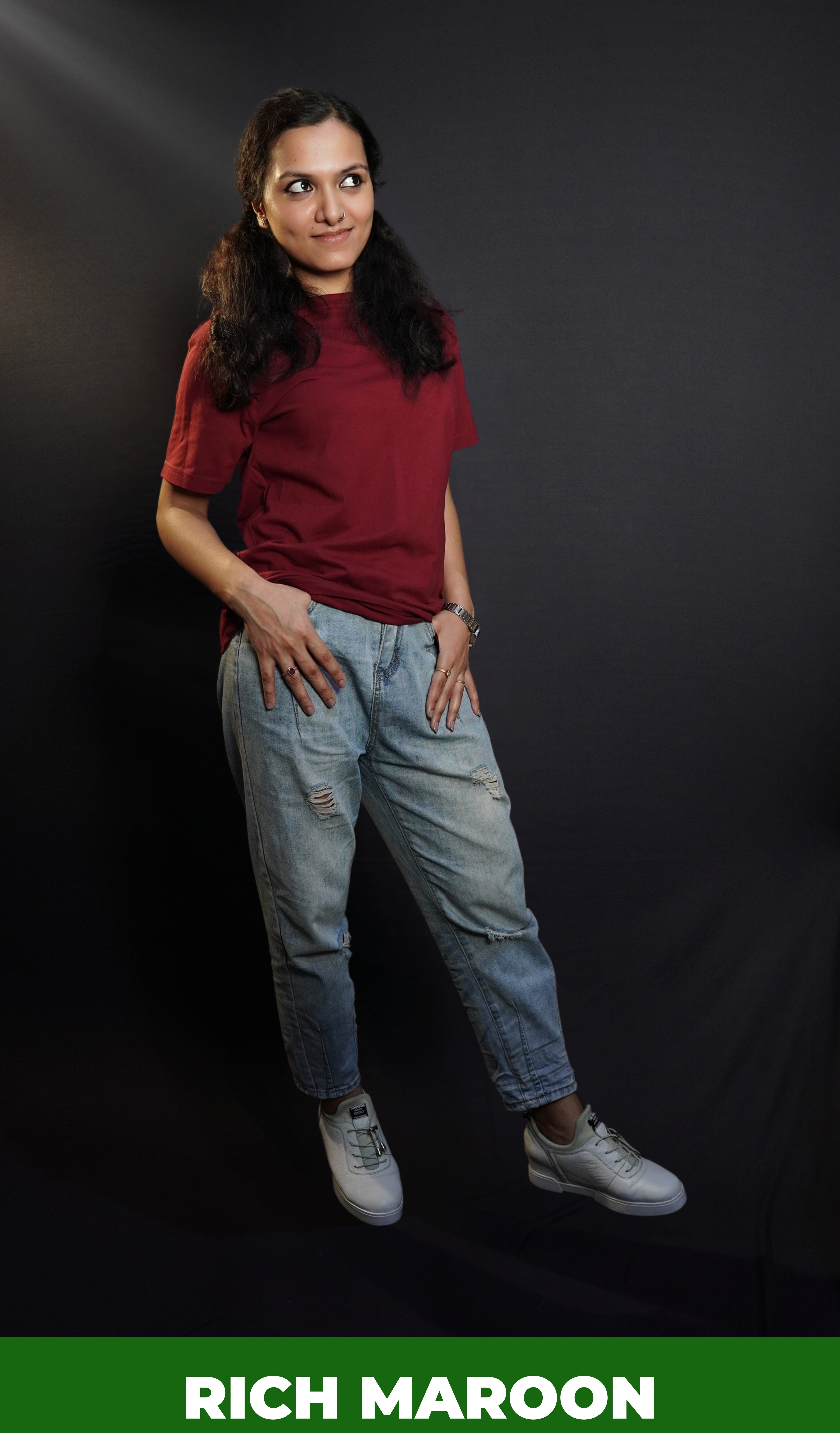 A woman wearing a short sleeved cotton stretchable rich maroon t-shirt, posing with her thumb inside the front pockets of her jeans, highlighting a stylish relaxed fit-Muselot
