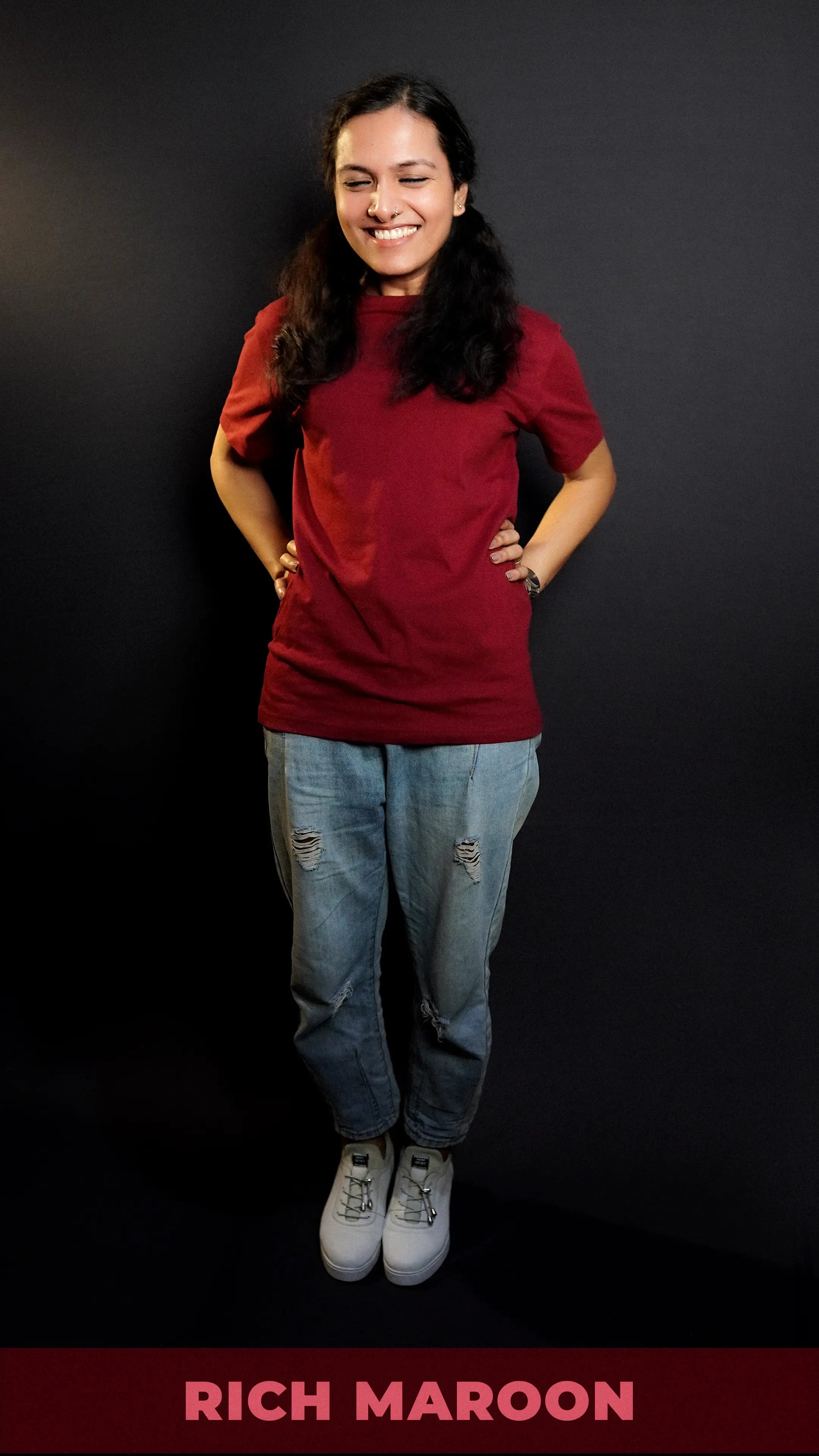 A cute model laughing hard posing with her hands on her waist, wearing a short sleeved quick drying round neck rich maroon t-shirt, showcasing a modish in vogue look-Muselot